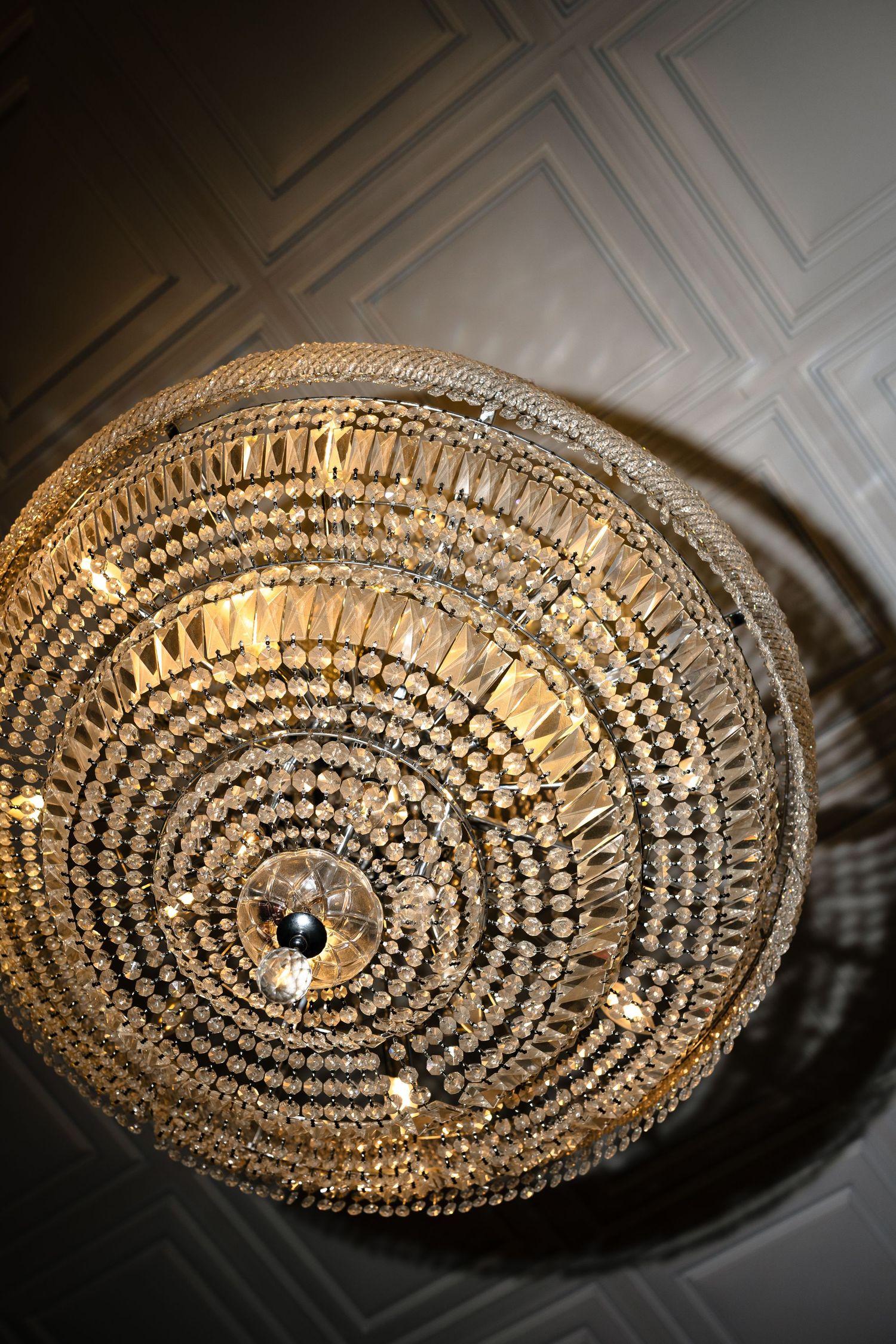 Close-up view of an ornate crystal chandelier with concentric circles of glass beads and prisms creating elegant lighting patterns.