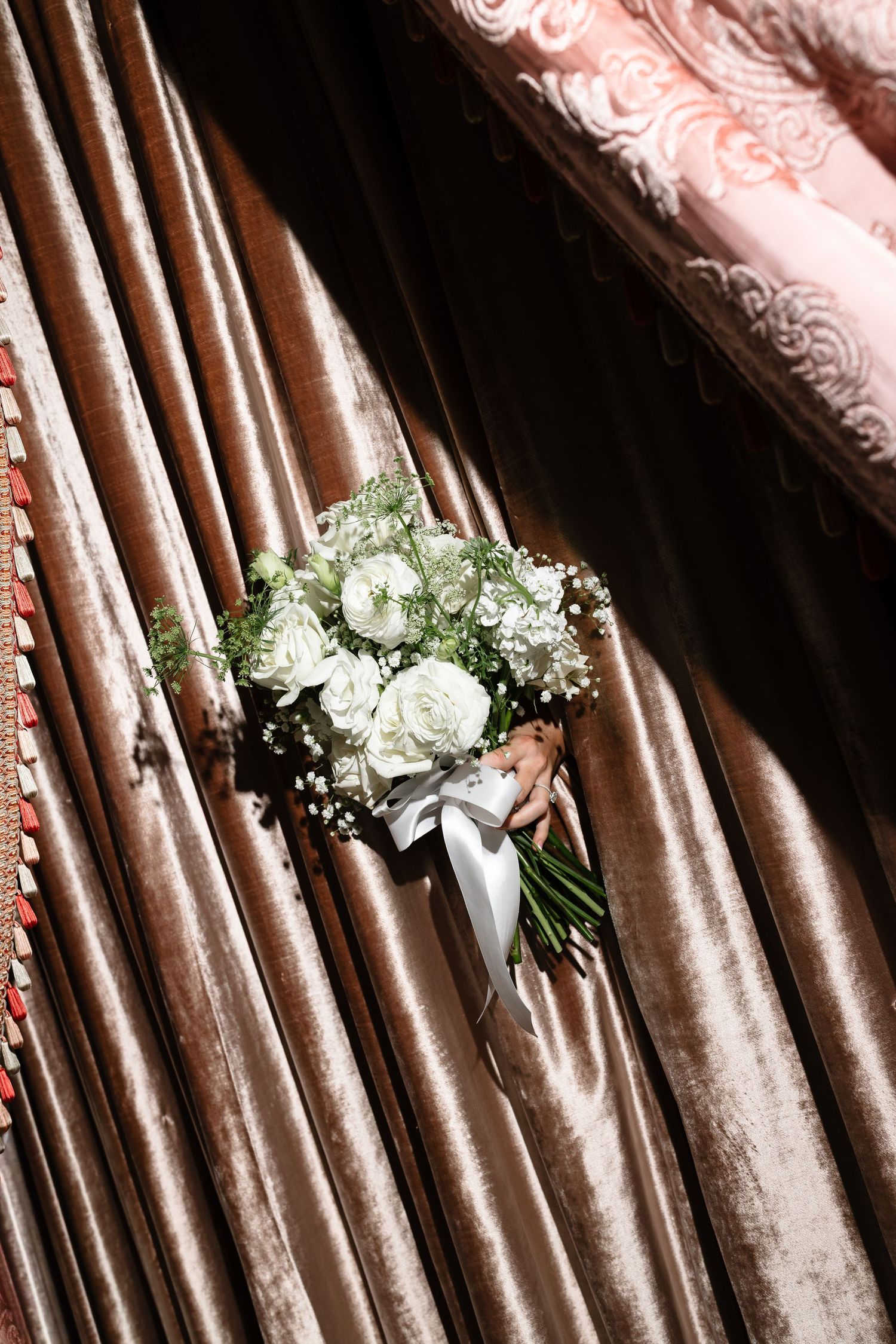 White rose and baby's breath floral bouquets arranged against a backdrop of shimmering rose gold curtains.