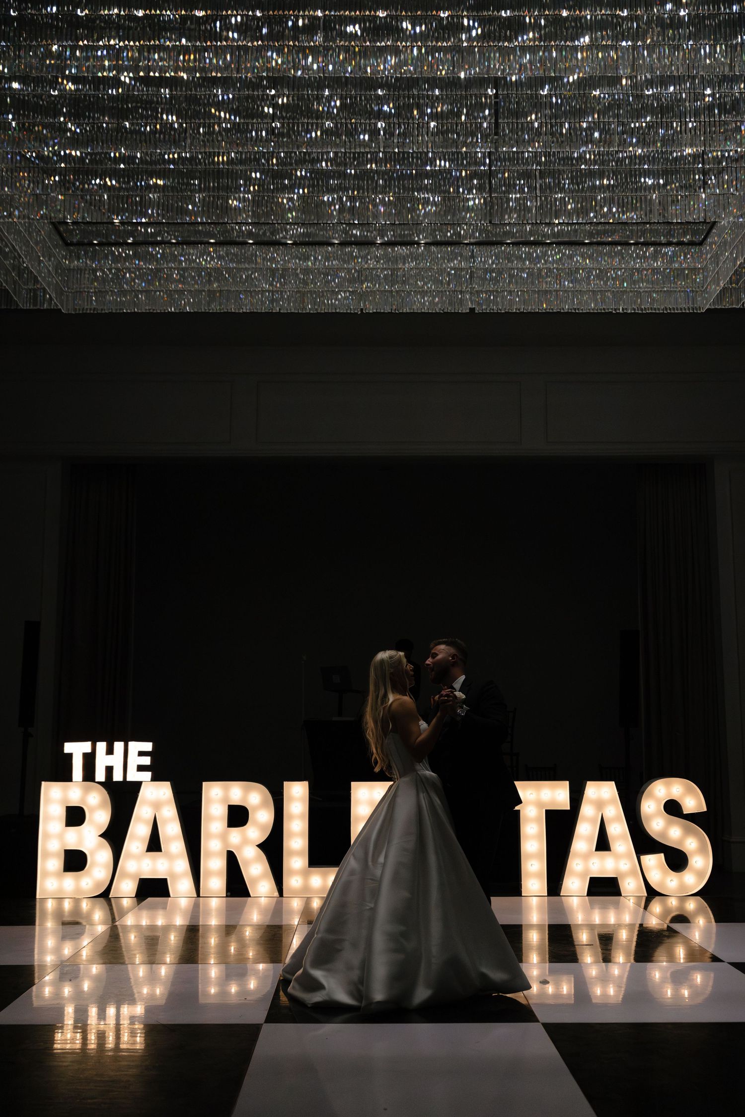 A series of illuminated letters spelling 'BARISTAS' create a dramatic light display against a dark background.