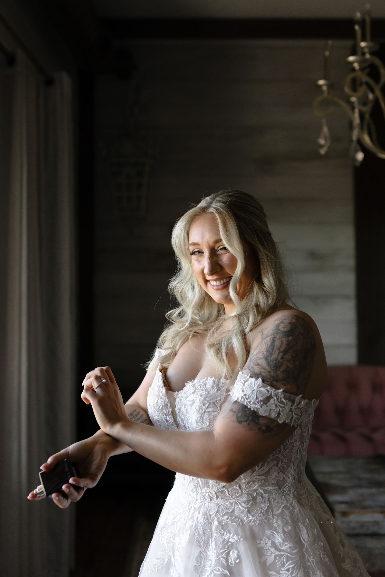 A bride in a white lace dress dances and twirls joyfully in a dimly lit room.