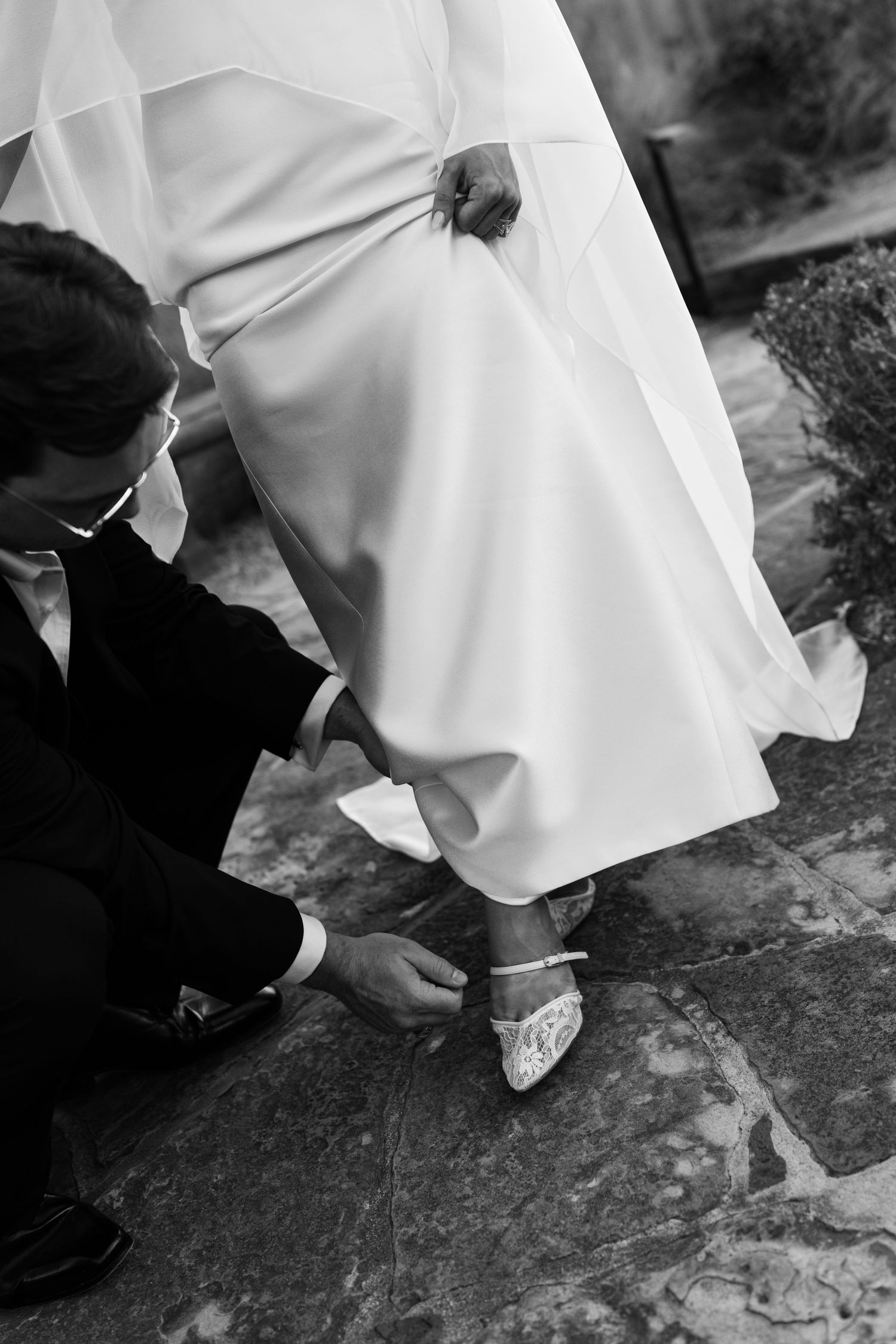 A black and white photo series showing close-up details of bridal shoes and dress hem on stone steps.