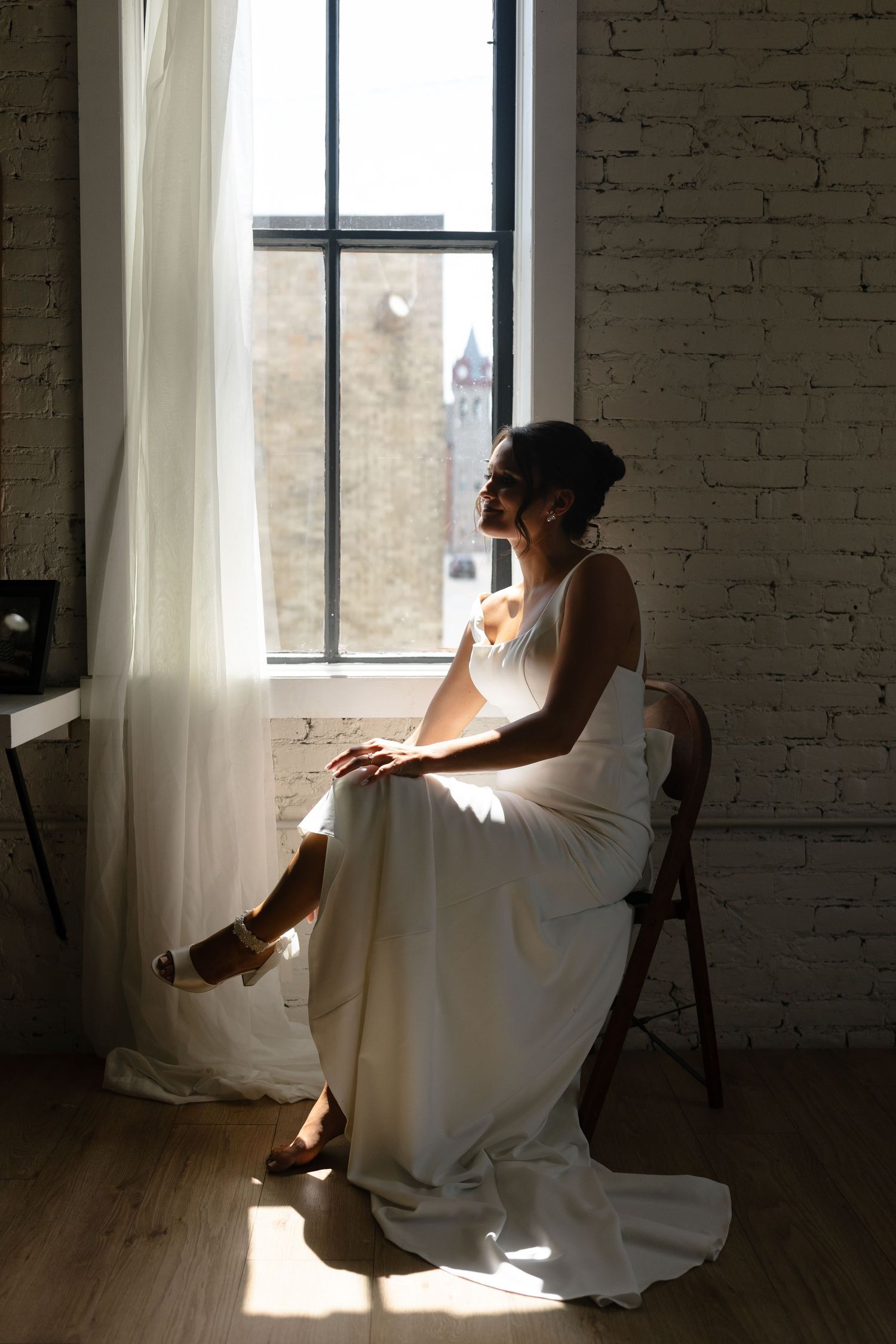 A series of artistic silhouette photos showing a figure in white near a sunlit window in an industrial loft space.