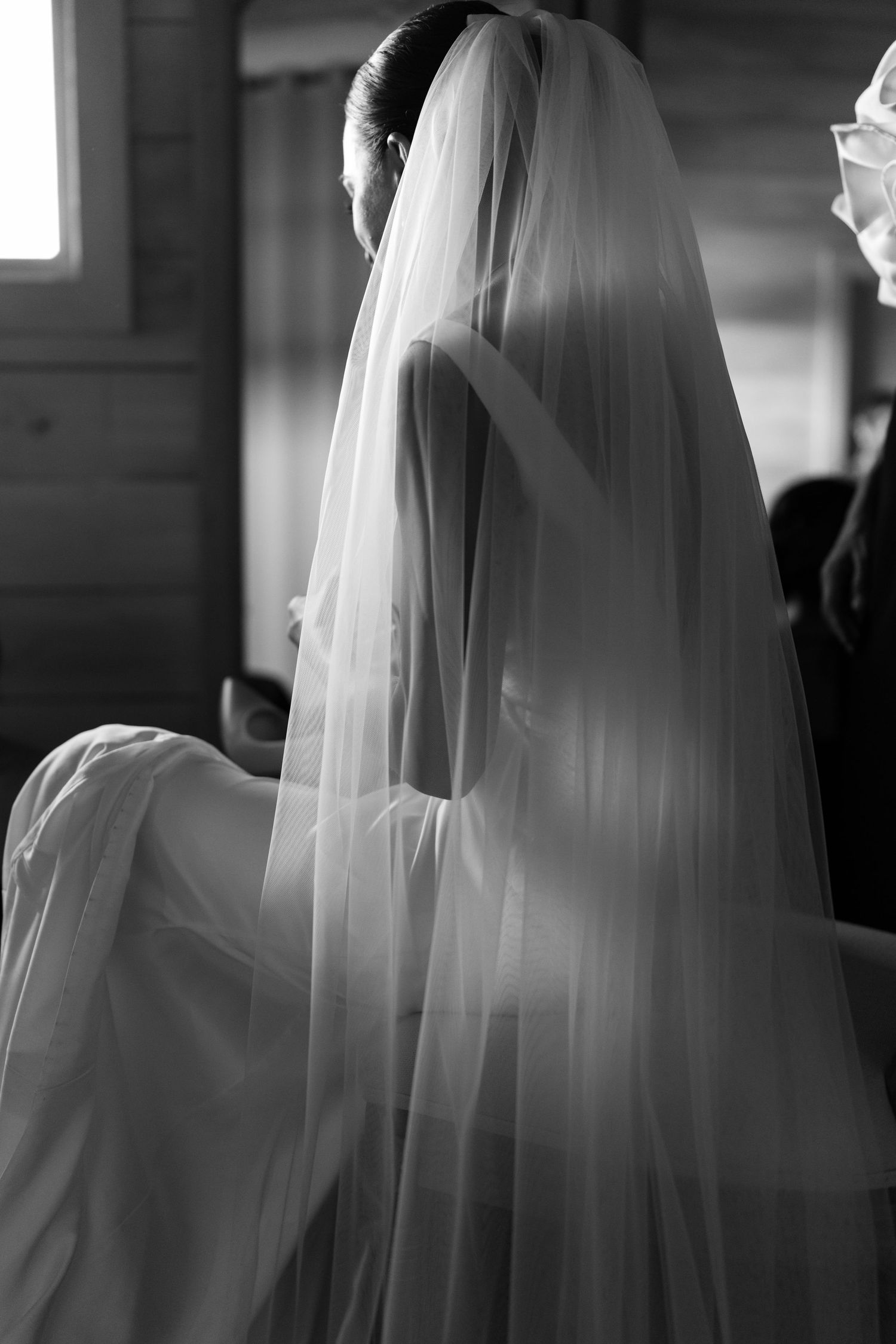 A black and white photo series showing a bride in a flowing veil from different angles during a wedding ceremony.