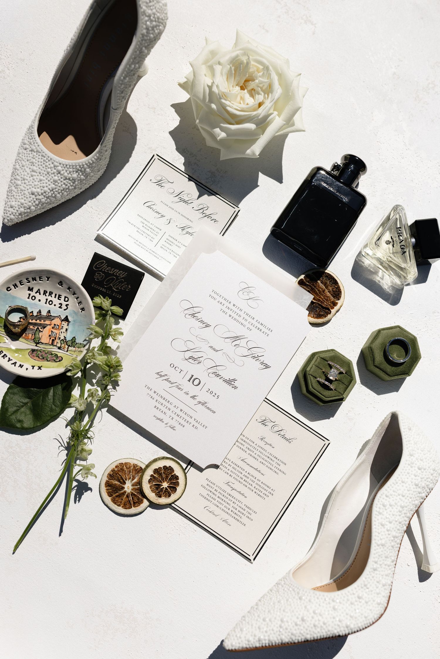 Wedding invitation suite with white roses, dried citrus, and elegant stationery displayed on white background with shoes.