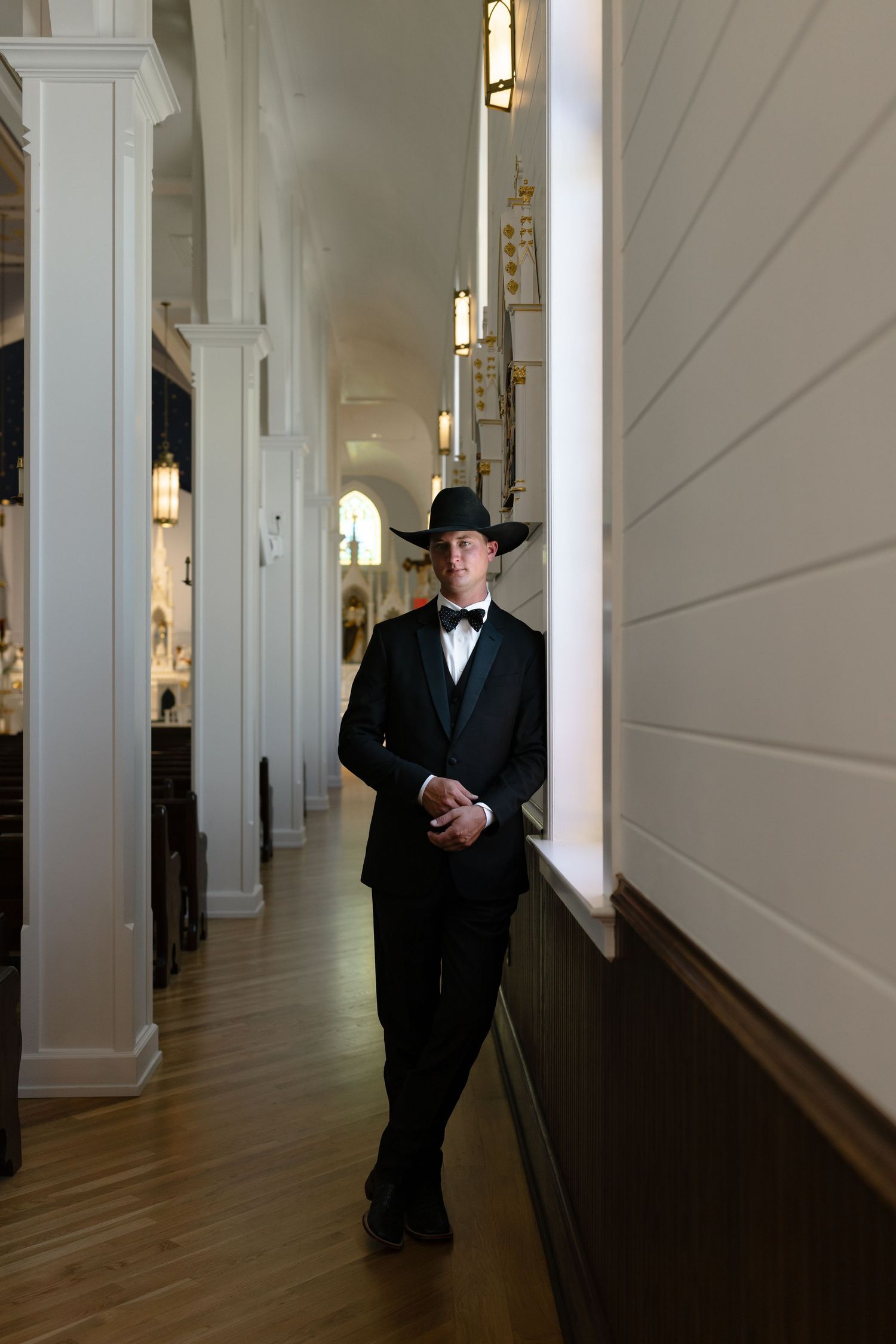 A sequence of five photos showing a person in a black suit and hat walking down a long white corridor.