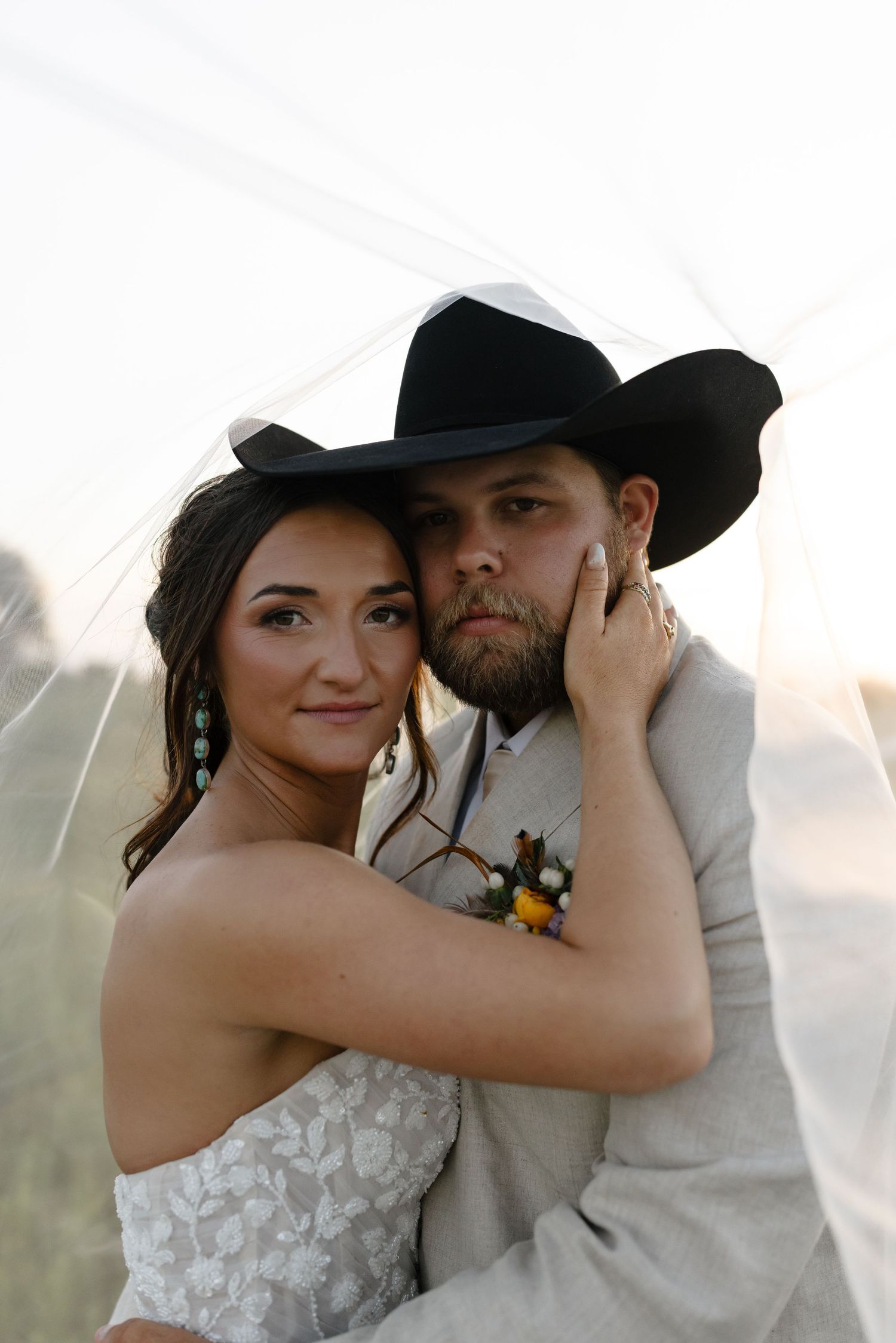 Intimate wedding portraits of a couple in cowboy hats against a soft sunset backdrop.
