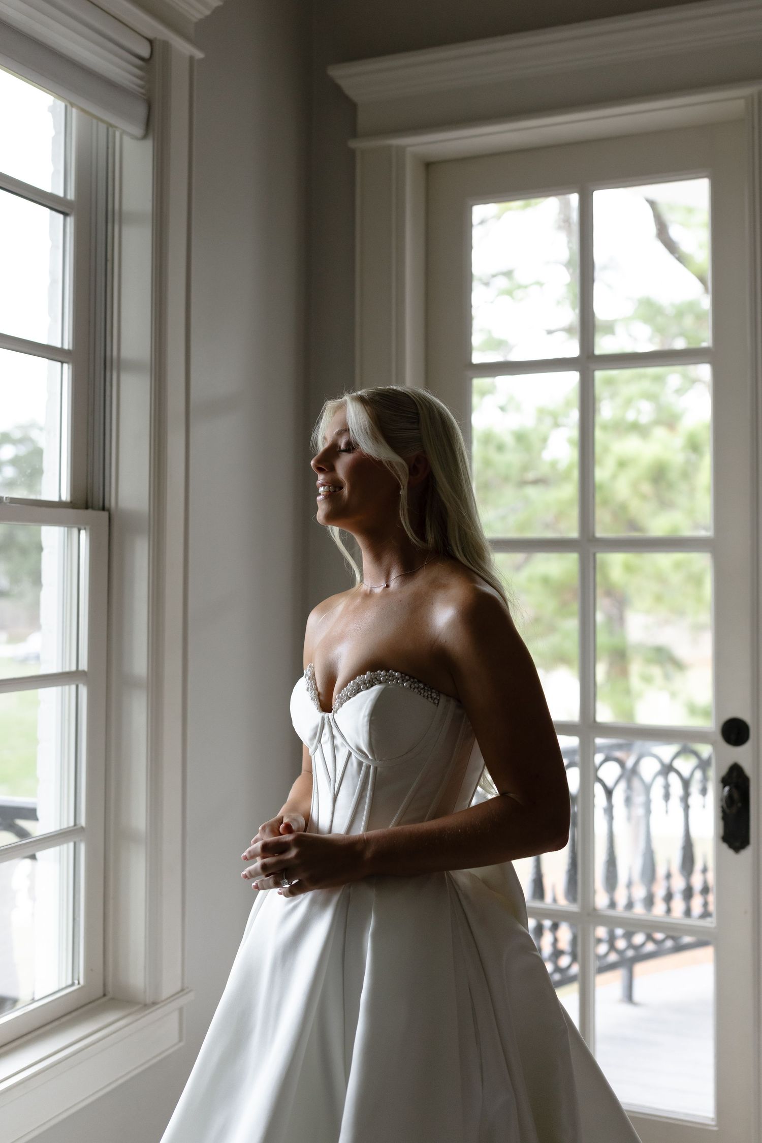 Four sequential photos show a person in a white dress leaning back against a bright window-lined wall.