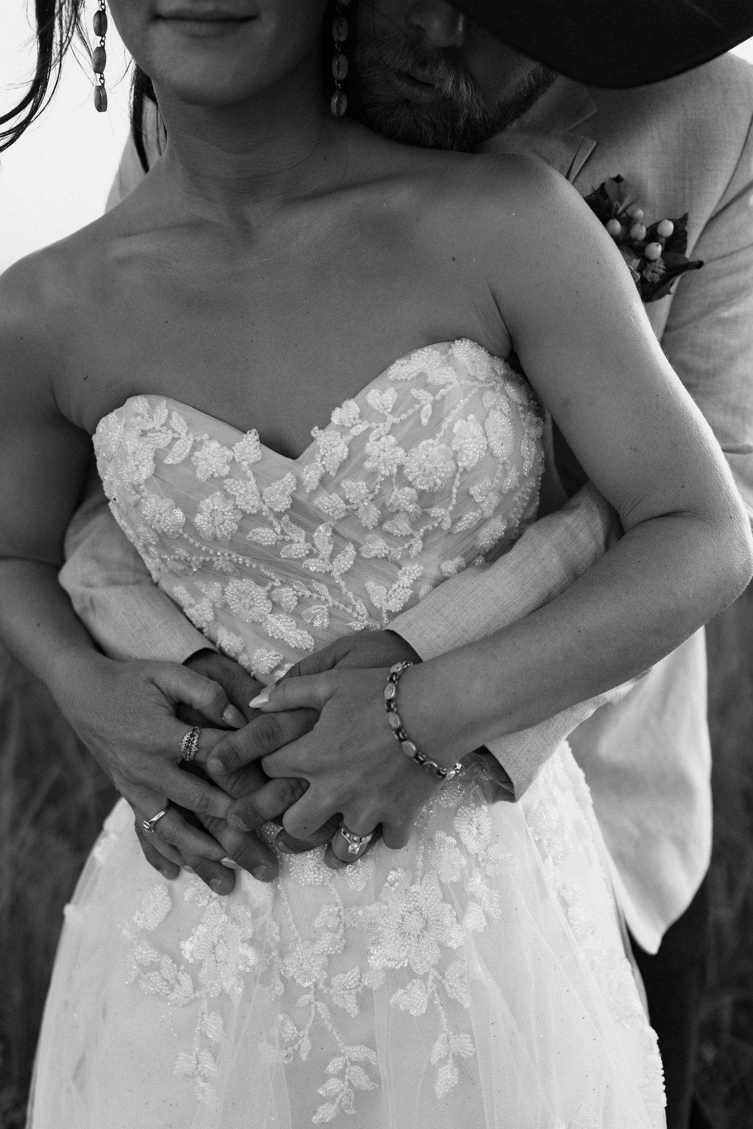A series of black and white photos showing details of a strapless wedding dress with delicate lace appliques.