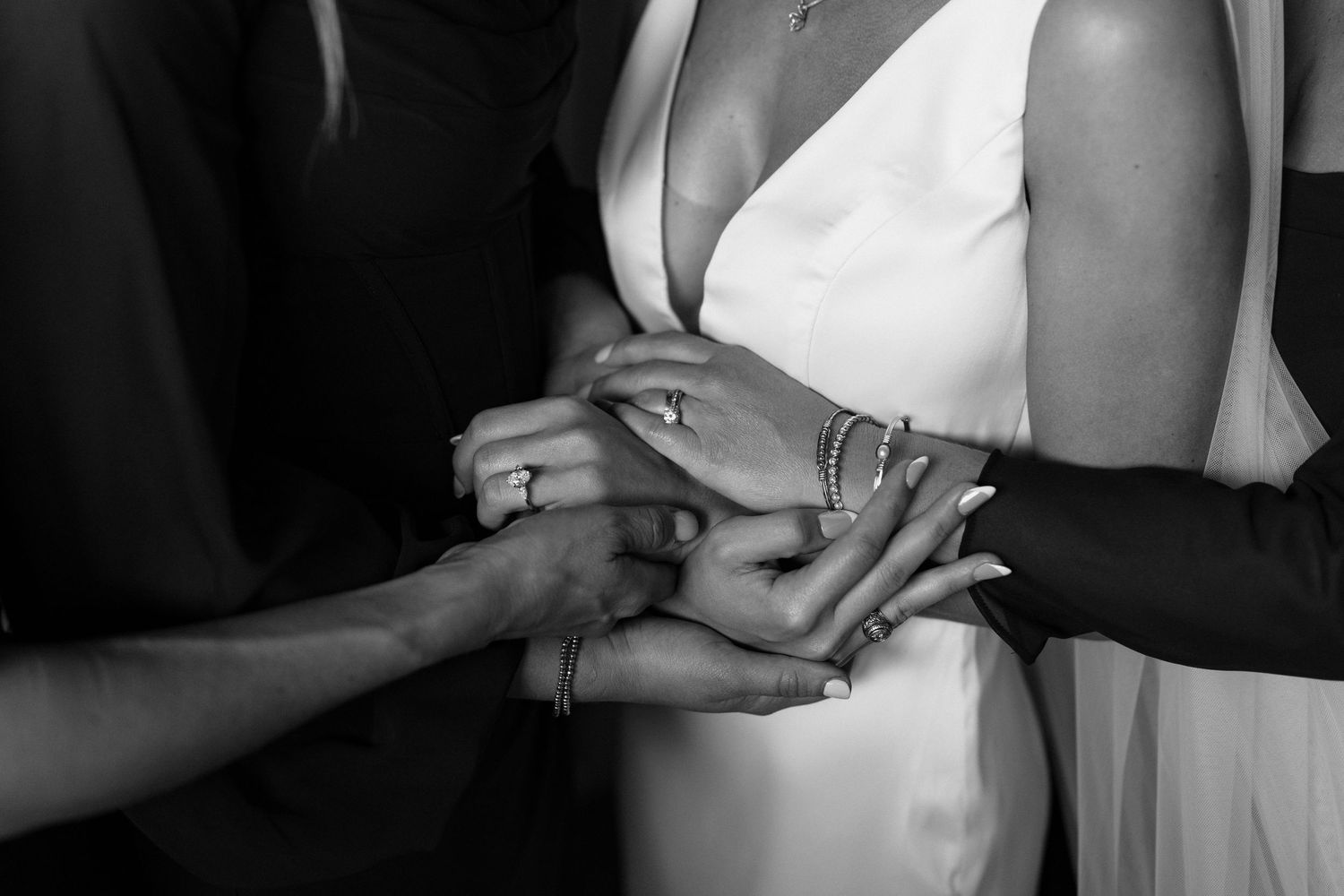 Black and white wedding photos showing close-up details of dress buttons, rings, and hands during a ceremony.