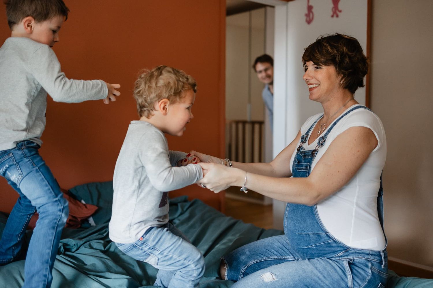 photo naturelle lifestyle d'une famille heureuse en seance photo de grossesse a Lille les enfants sautent sur le lit avec maman