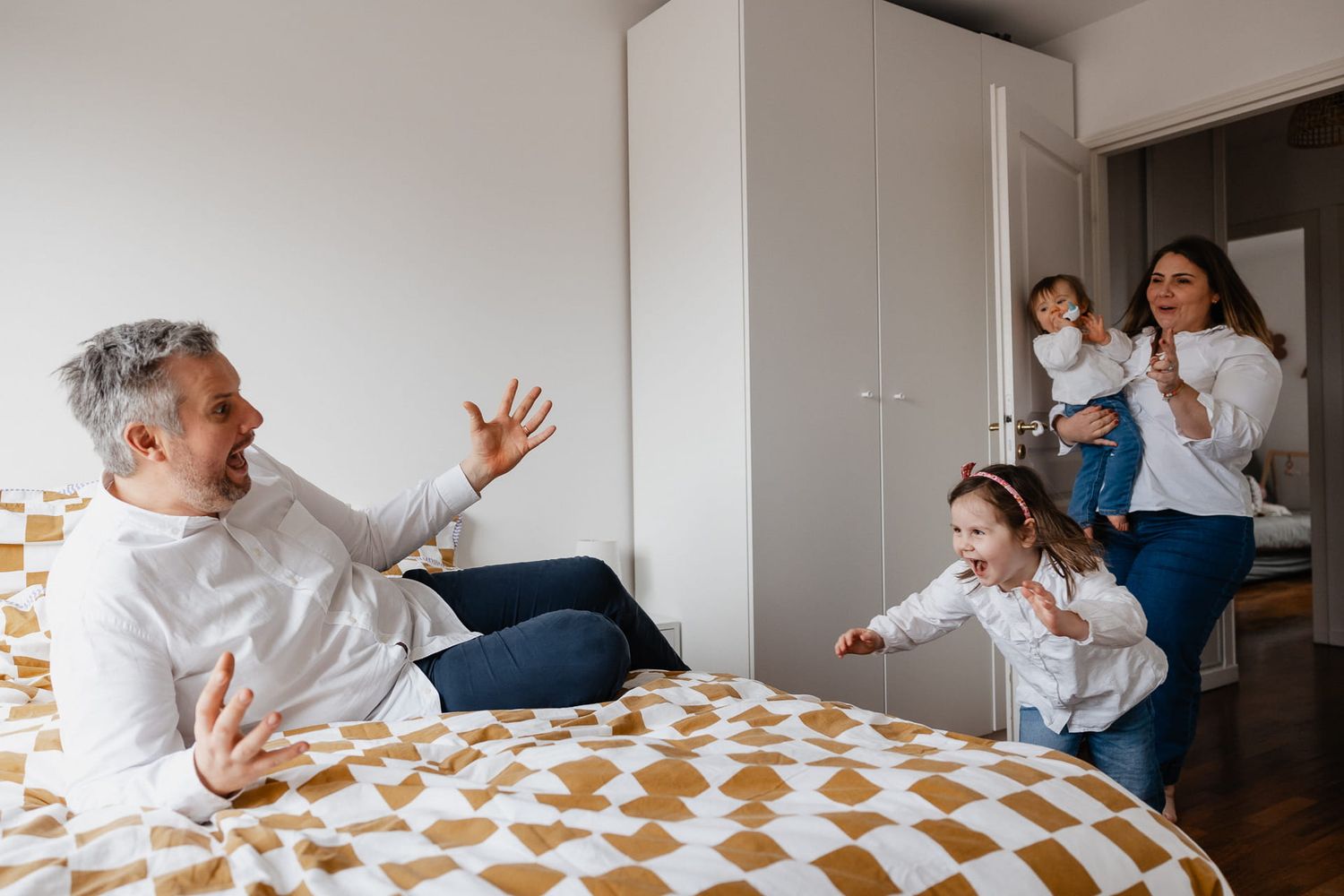 Famille de 4 jouant a cache cache, scene de vie pleine d'energie capturee par une photographe de famille a domicile a Lille