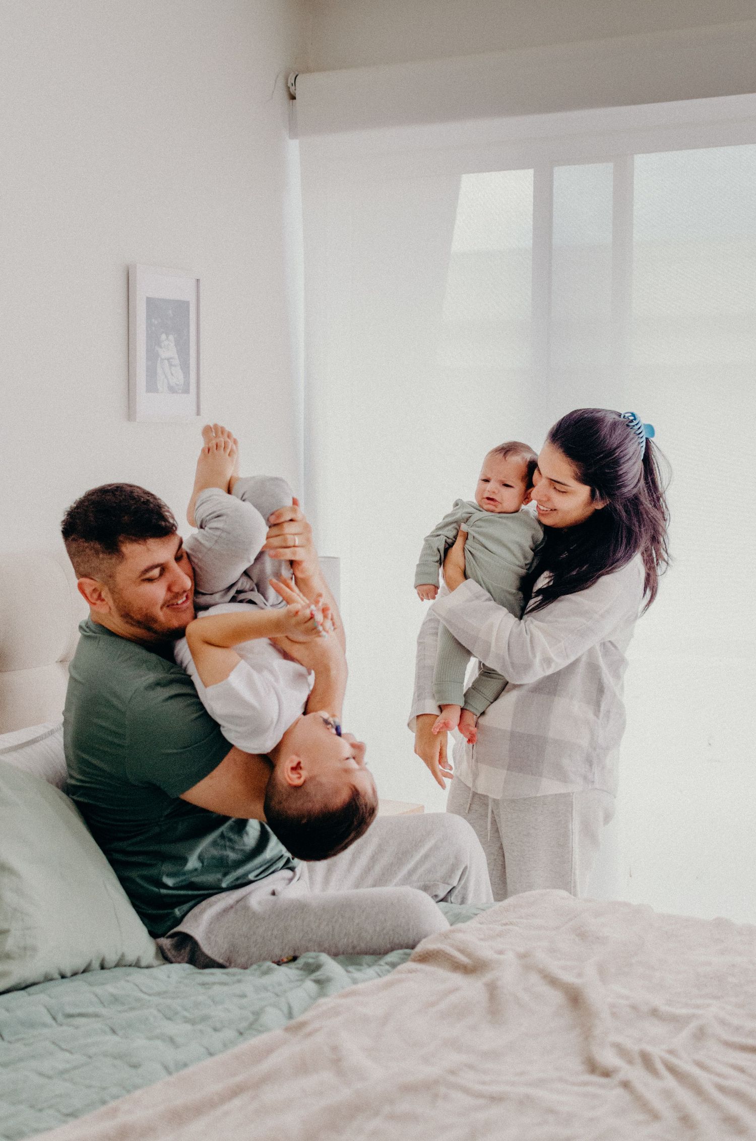 A couple shares playful and intimate moments while relaxing together on a bed with white linens.