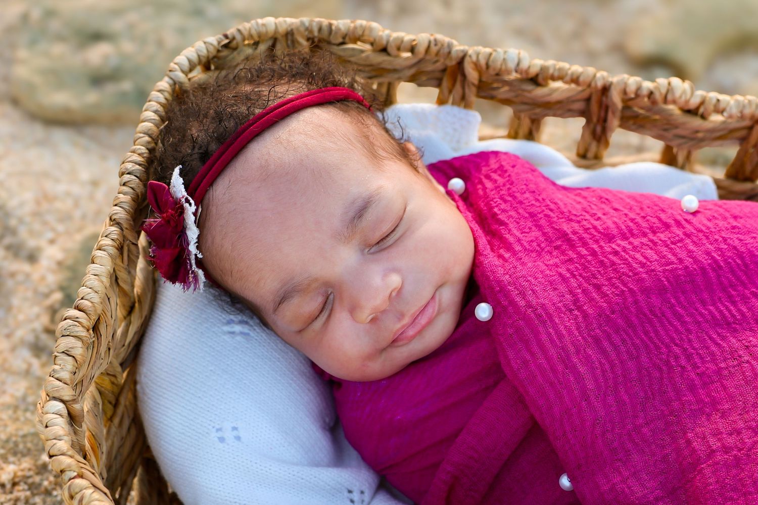 A person in a pink sweater rests peacefully in a wicker seat with sunlight streaming across their face.