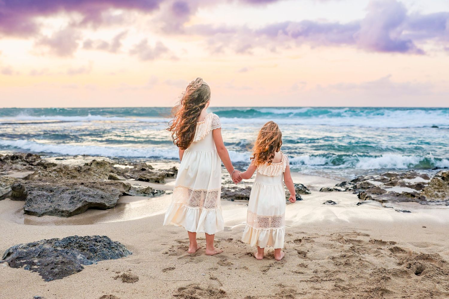 A beachside photo series showing people in white dresses walking along a rocky coastal shore at sunset.