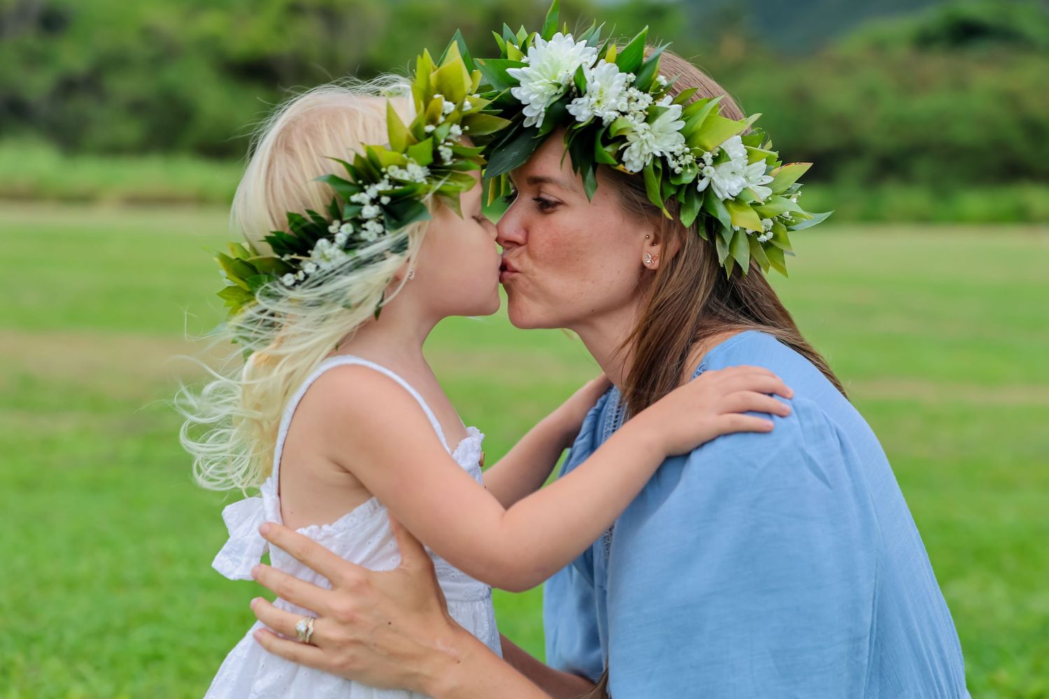 An intimate embrace outdoors with decorative floral headpieces against a green natural background.