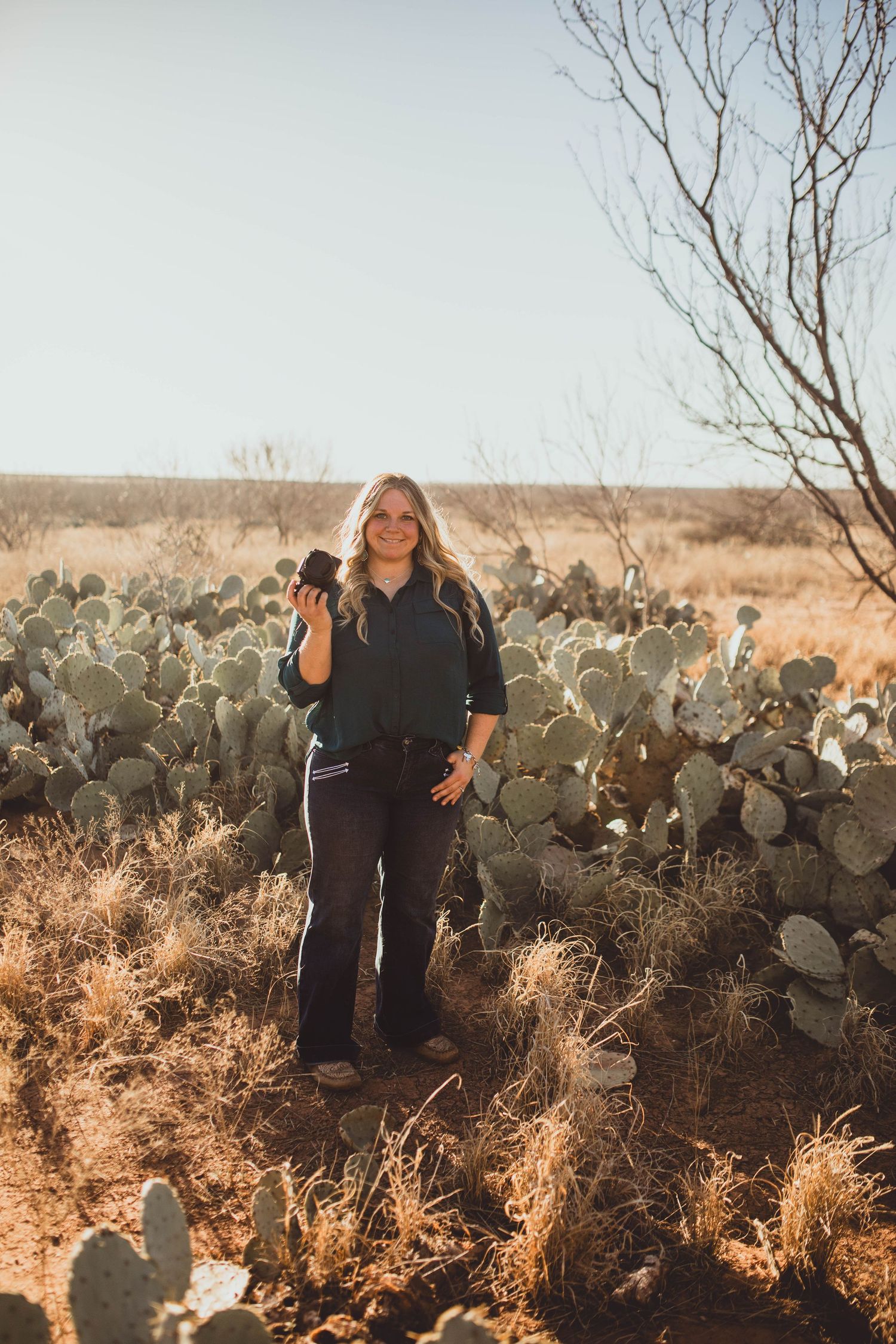 Desert portrait session with photographer amid prickly pear cactus during sunset.