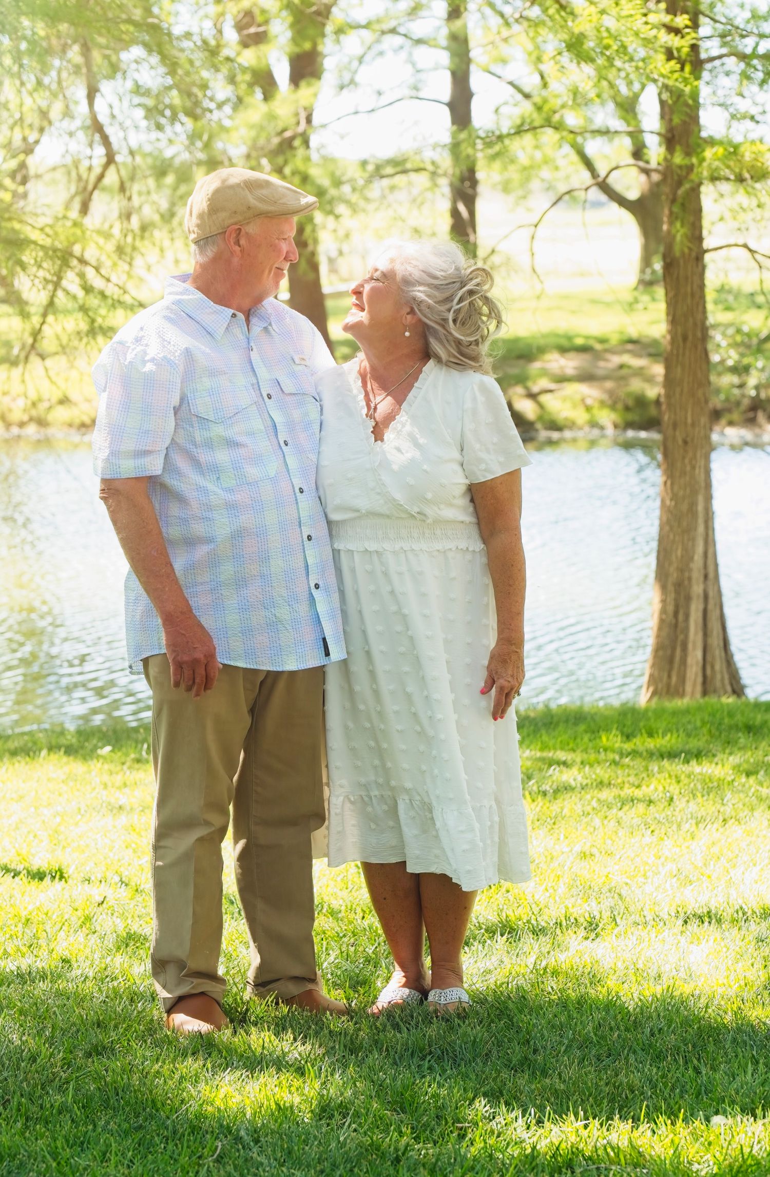 Outdoor family photo session with people standing on grass near a lake.