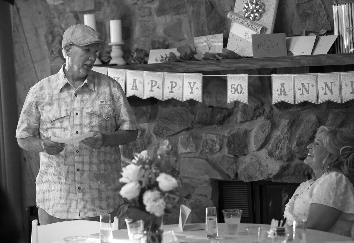 People celebrating at a party with decorative banners and tables visible in the background.
