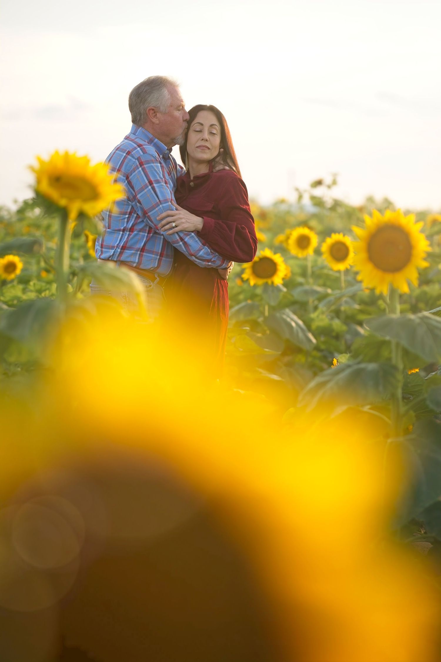 Romantic embrace among blooming sunflowers during golden hour sunset.