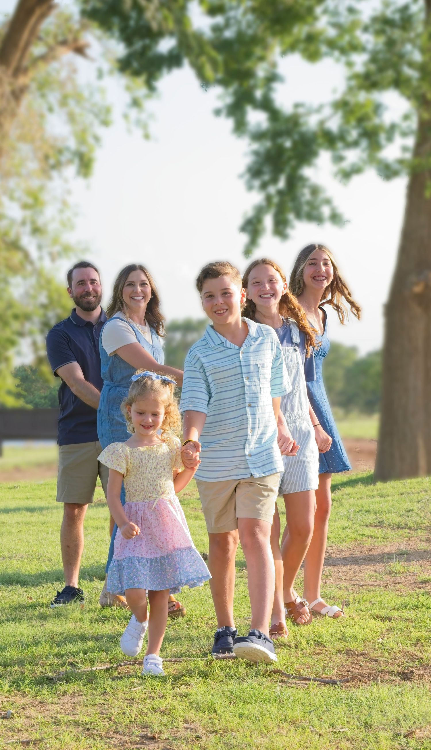 Group enjoying a sunny afternoon together on a grassy hill near trees.