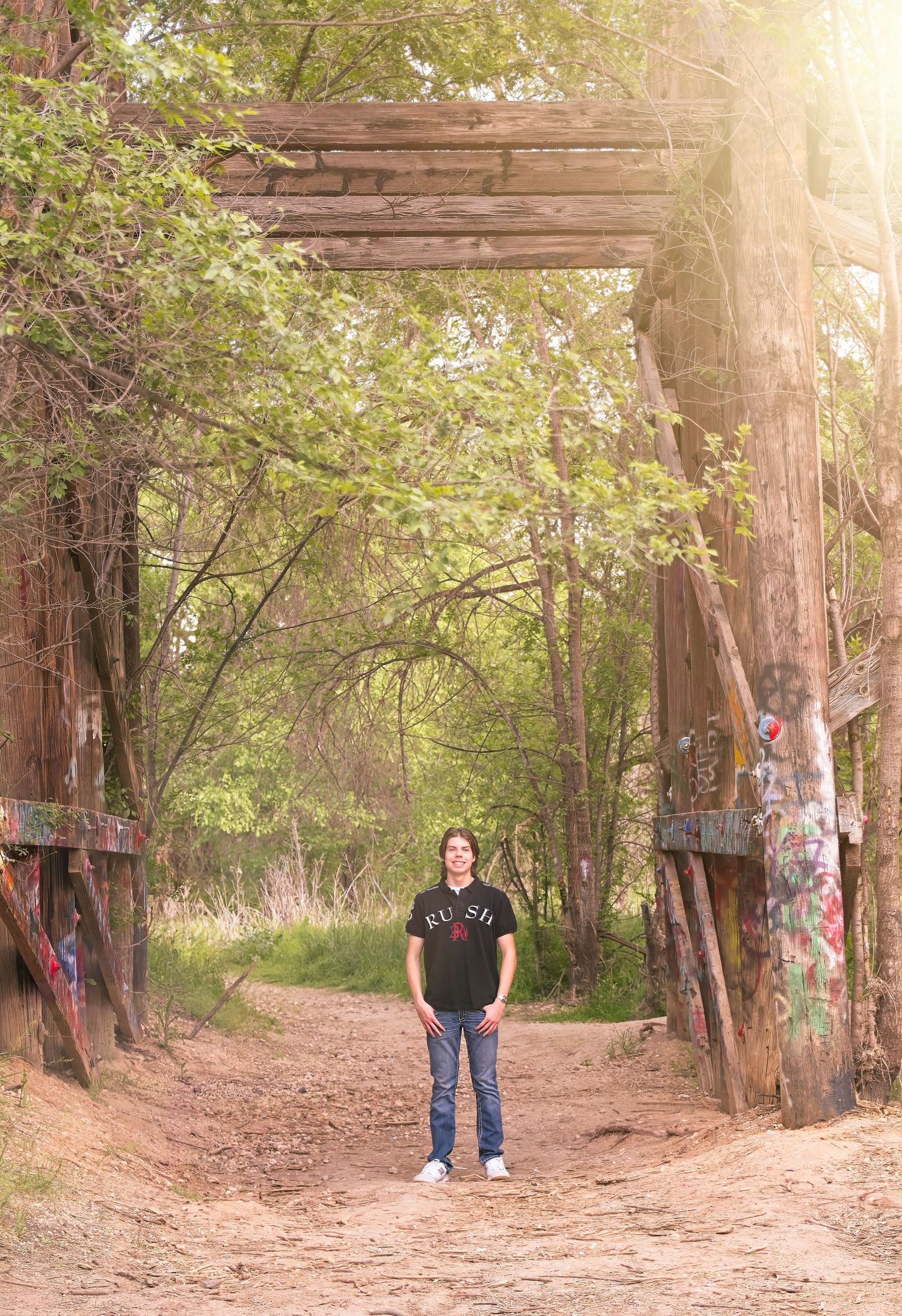 Rustic wooden archway on a nature trail with graffiti-covered posts.