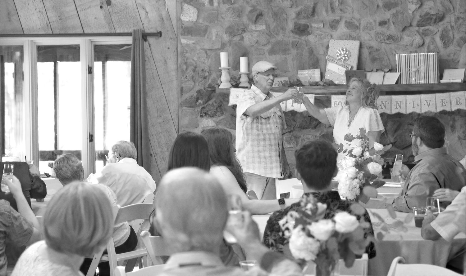 A large group of people gathered indoors for a celebratory event with tables and decorations.