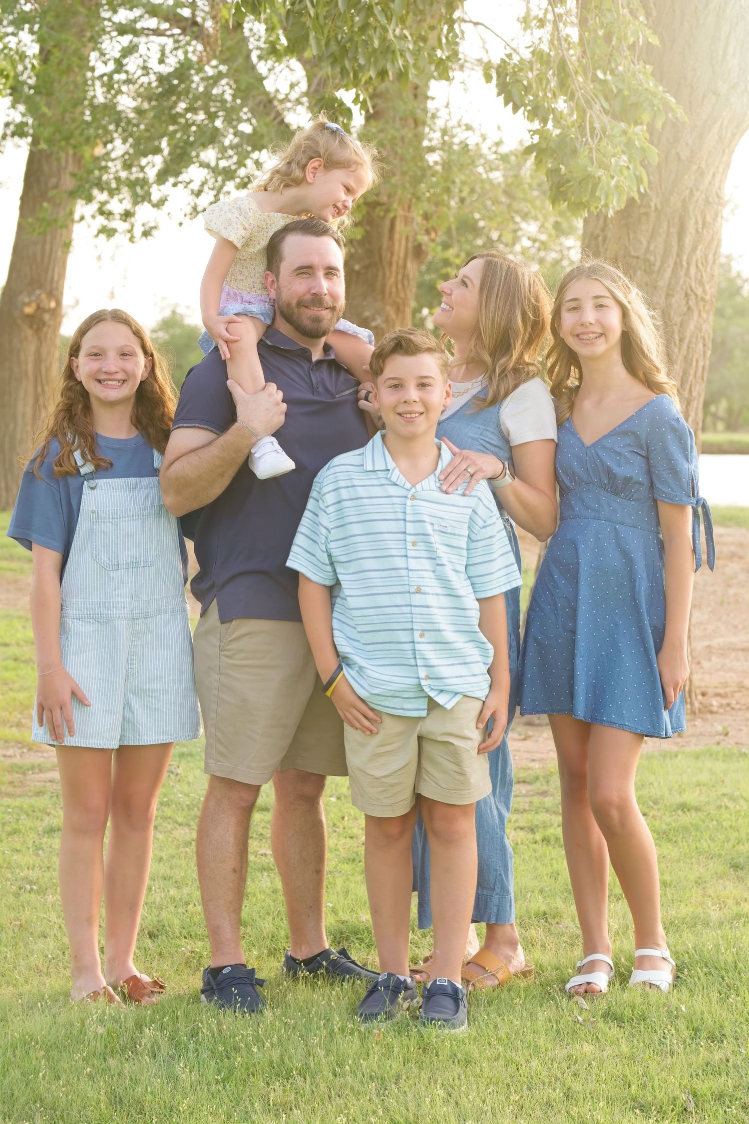 Family posing together for a portrait outdoors on a sunny summer day.