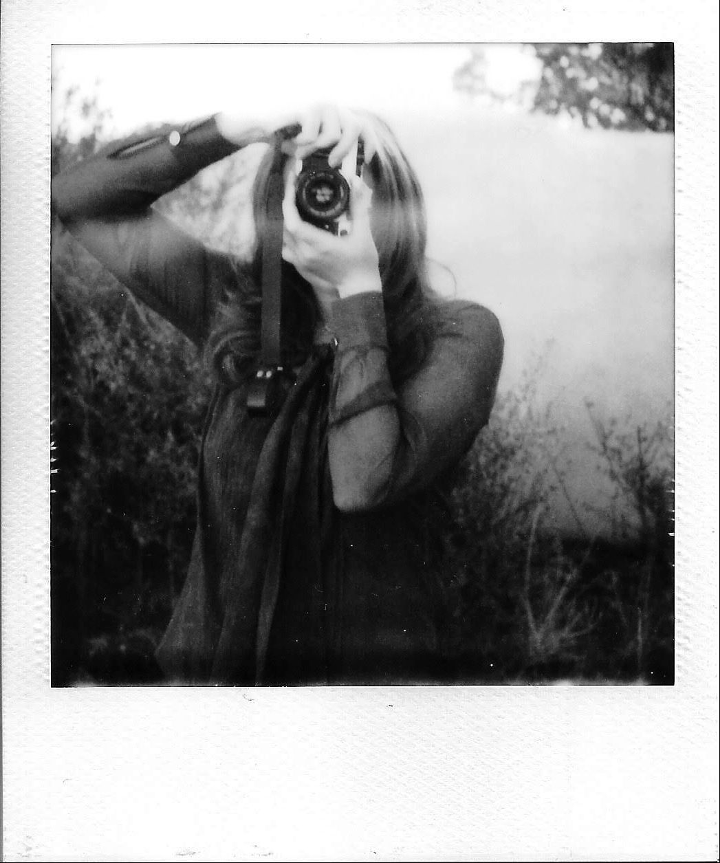 A black and white image of someone looking through a vintage camera lens.