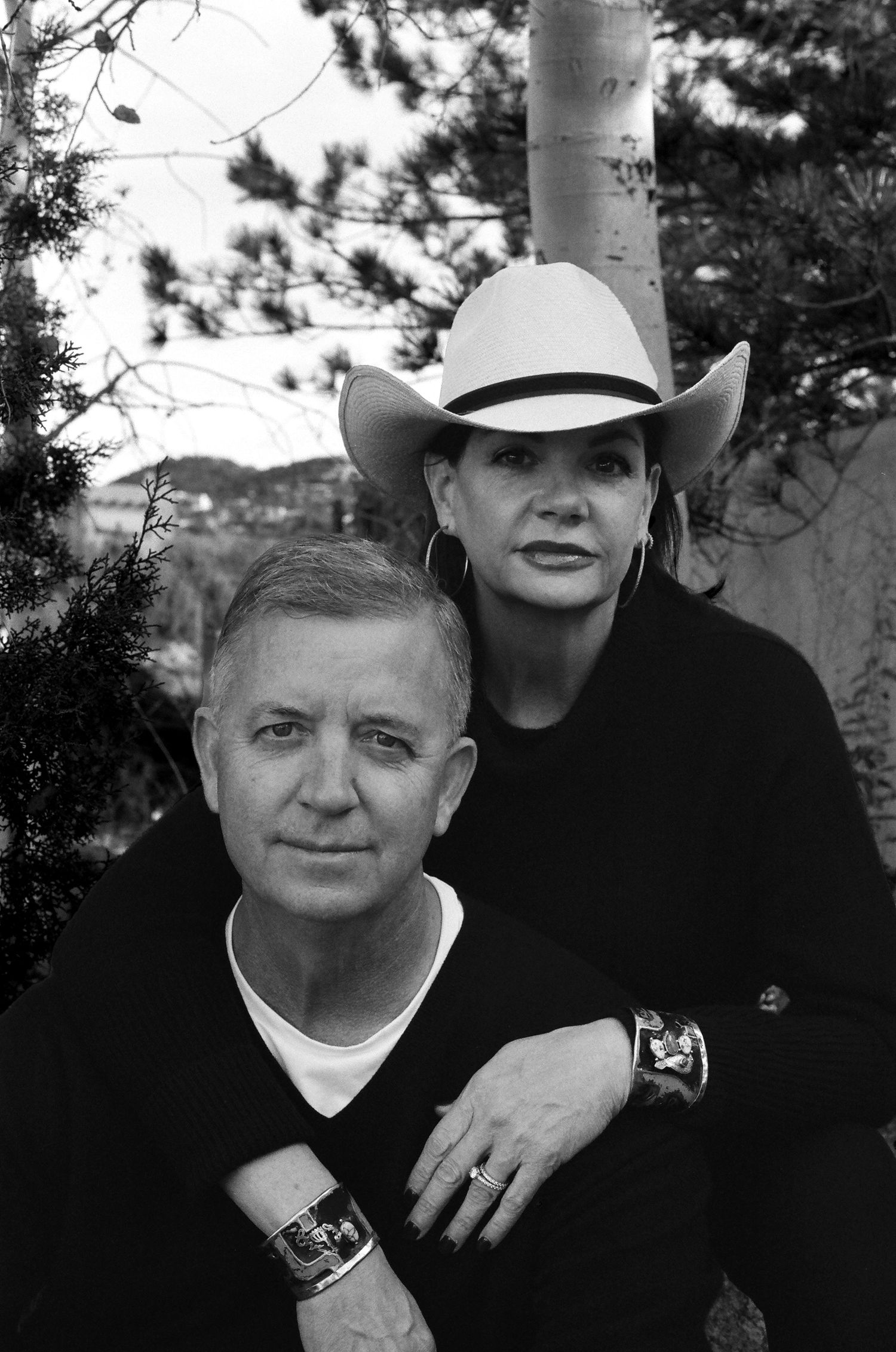 Black and white outdoor portrait featuring two people in western style with white cowboy hat and casual attire near an aspen tree.