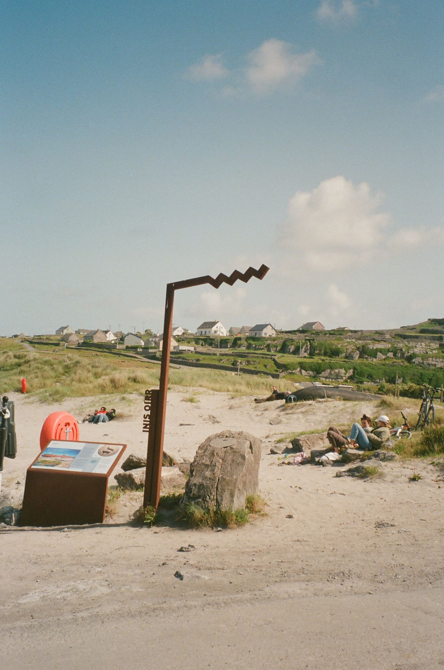 Desert landscape with wooden poles and a small red structure against clear blue skies.