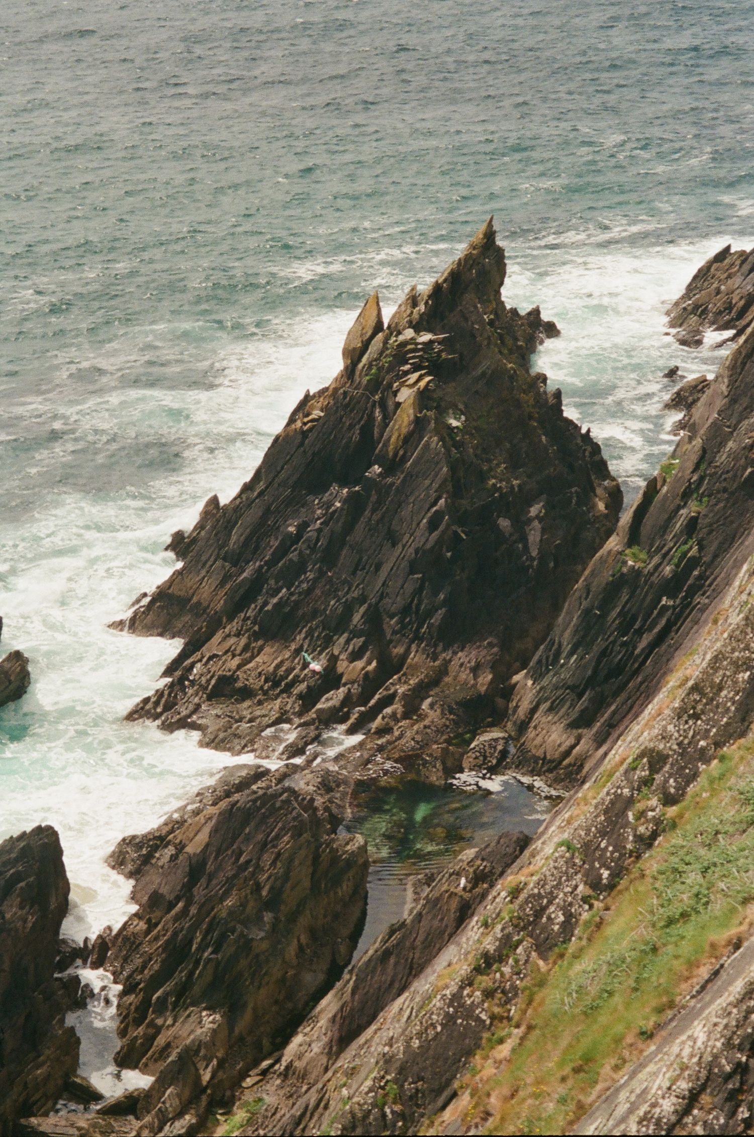 Jagged coastal cliffs rise dramatically from the churning sea, creating a rugged and dramatic seascape along the coastline.
