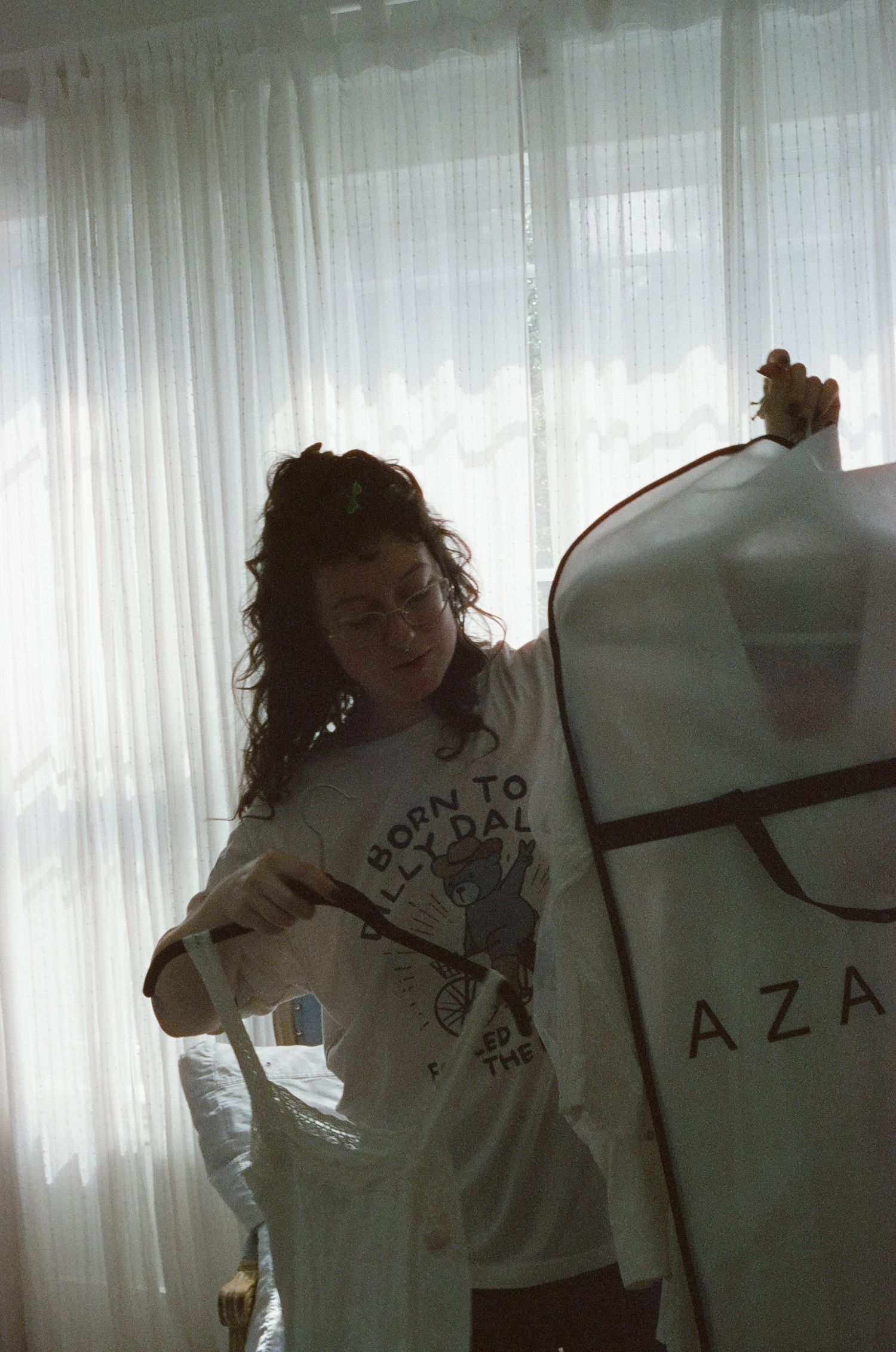 Vintage film photo of someone wearing a Born to Rock t-shirt standing beside a curtained window.