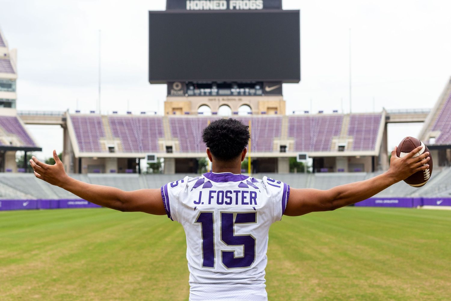 TCU football player wearing jersey number 15 stands with outstretched arms on the field at Amon G. Carter Stadium.