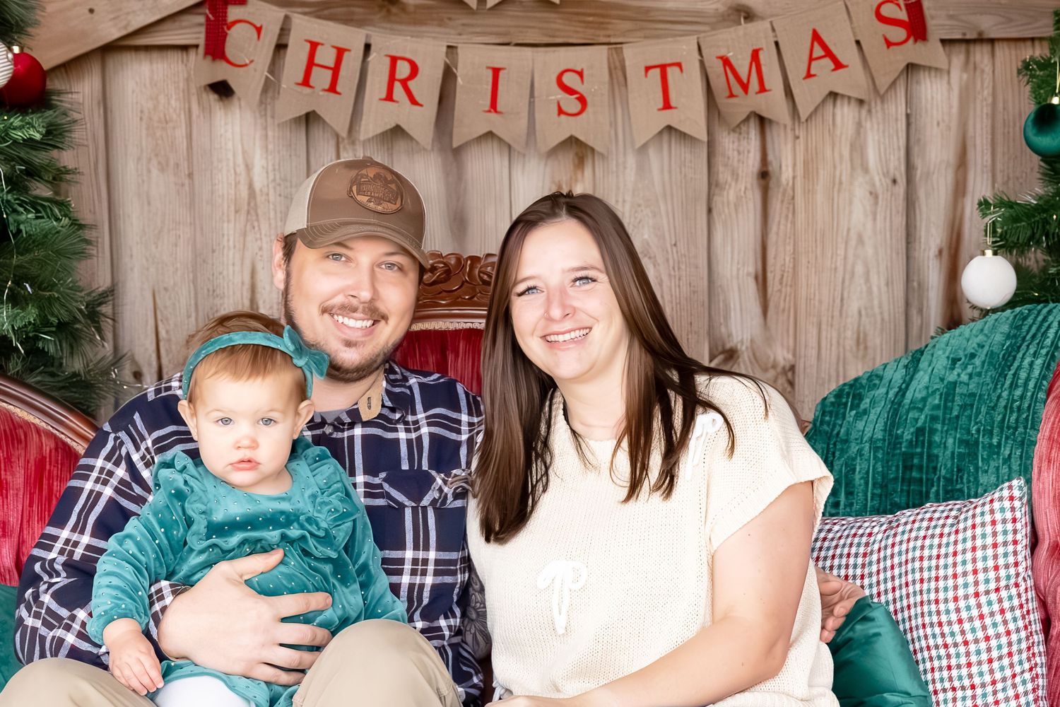 A festive Christmas photo banner hangs on a rustic wooden wall with evergreen garland decorations.