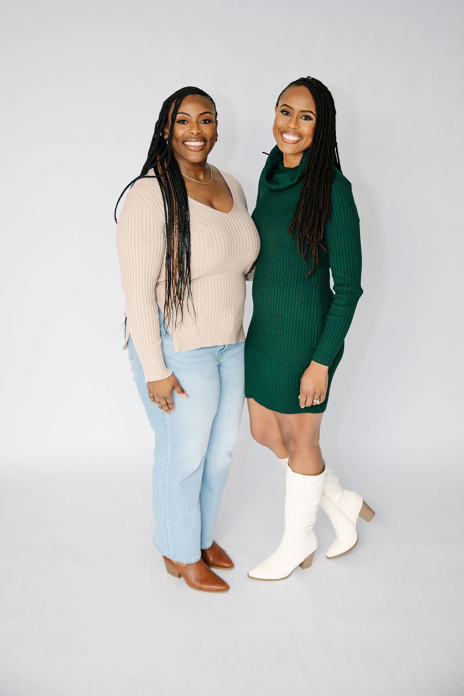 Two people in contrasting sweaters and light jeans pose together against a white backdrop.