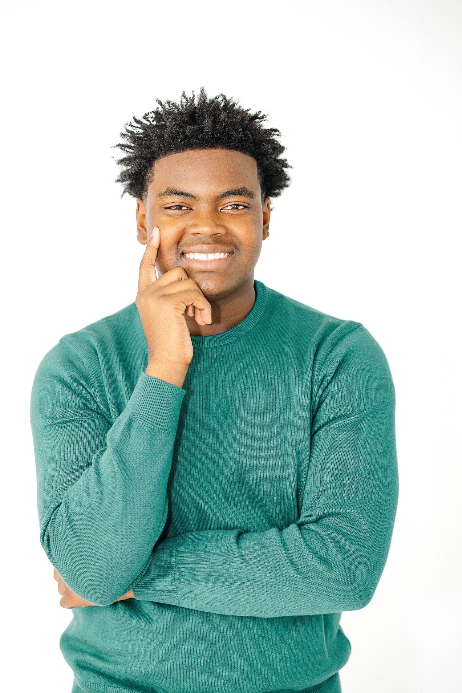 Person in green sweater makes playful expressions against white background in series of headshots.