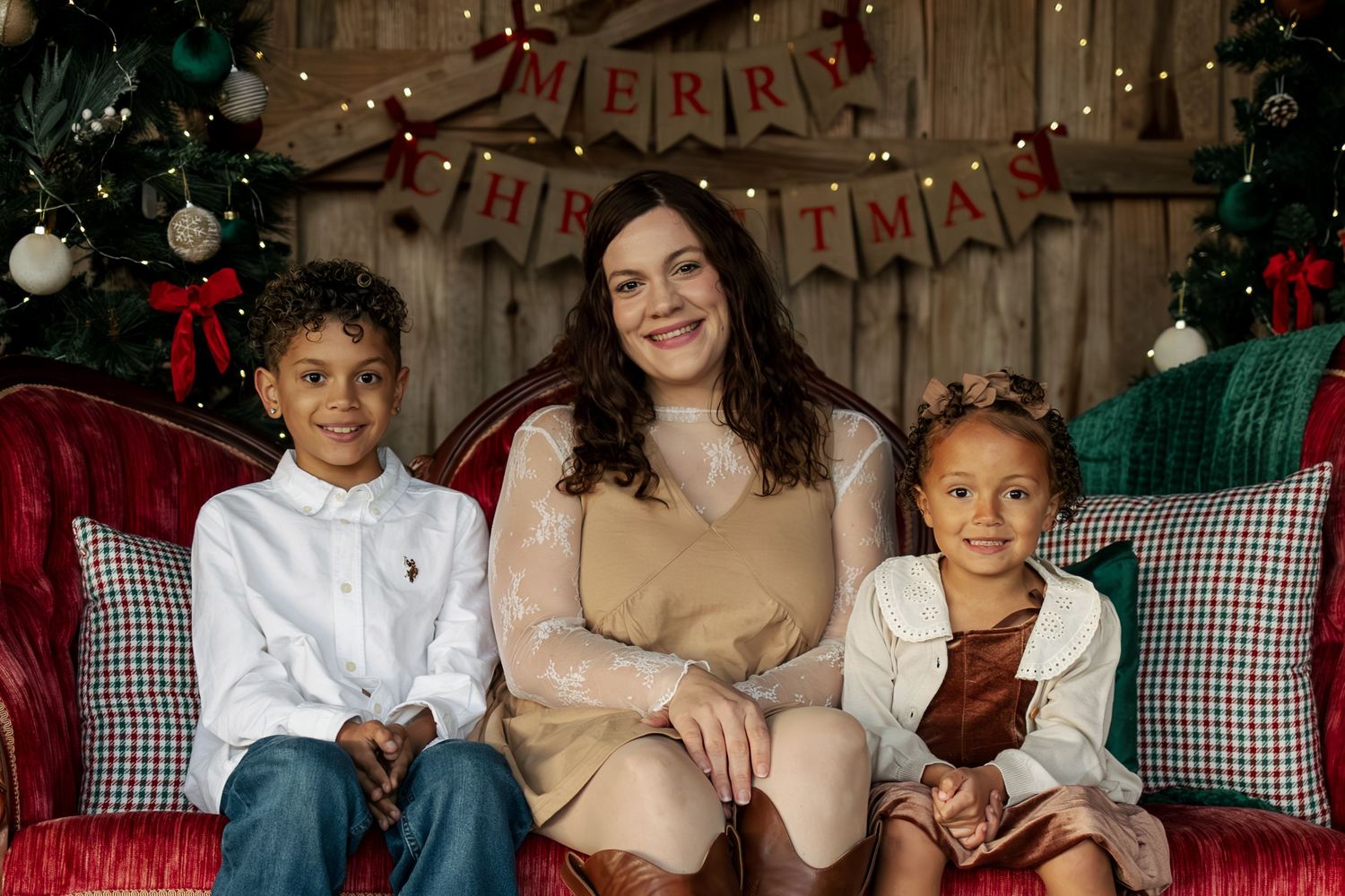 A cozy Christmas portrait on a plaid couch with holiday decorations and 'Merry Christmas' banner in the background.