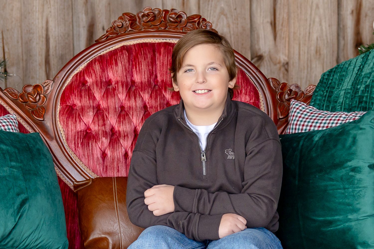 Rustic wooden backdrop with ornate red velvet throne and teal accent pillows.