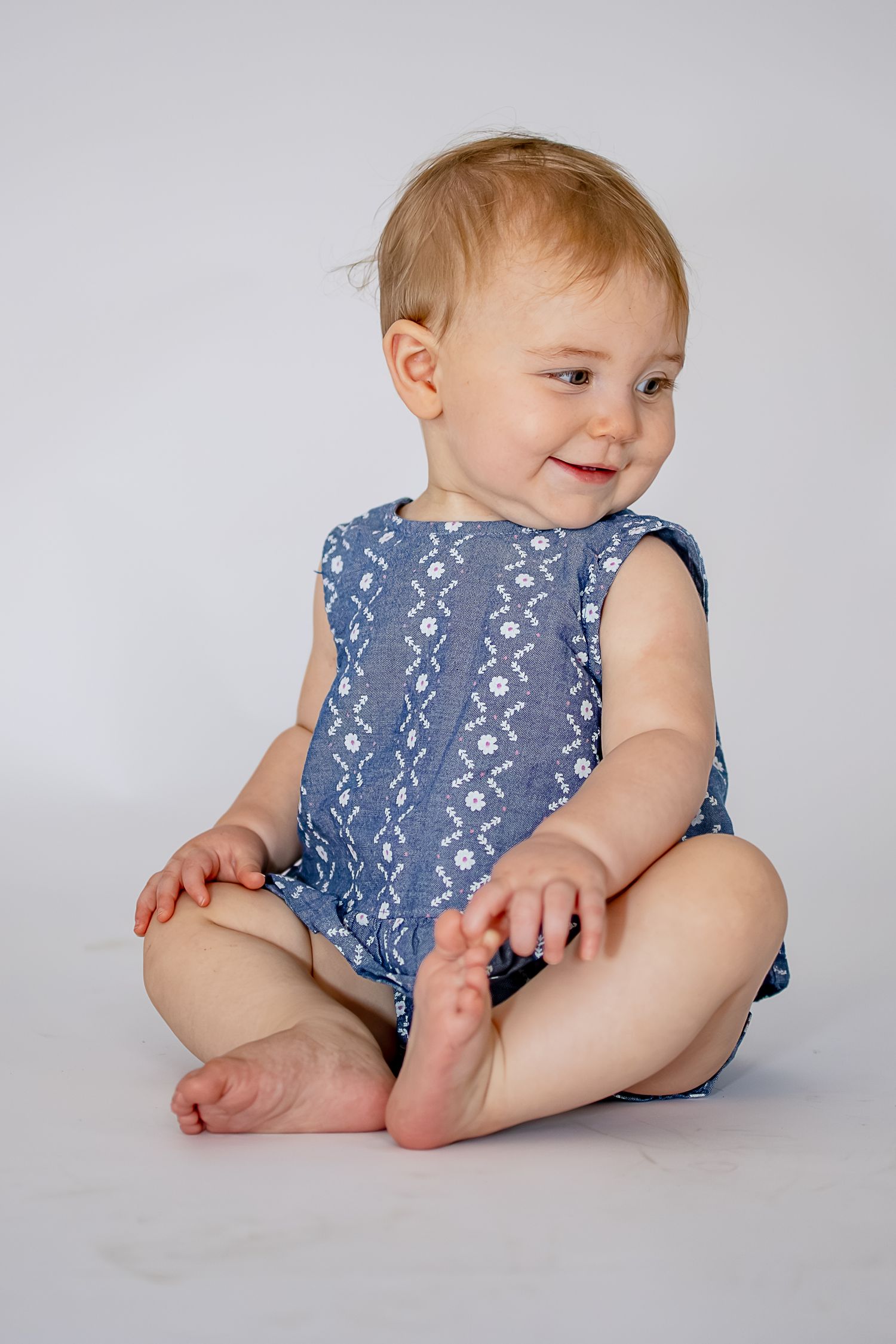 Baby wearing blue patterned romper sits on white backdrop in progressive poses showing movement and playfulness.