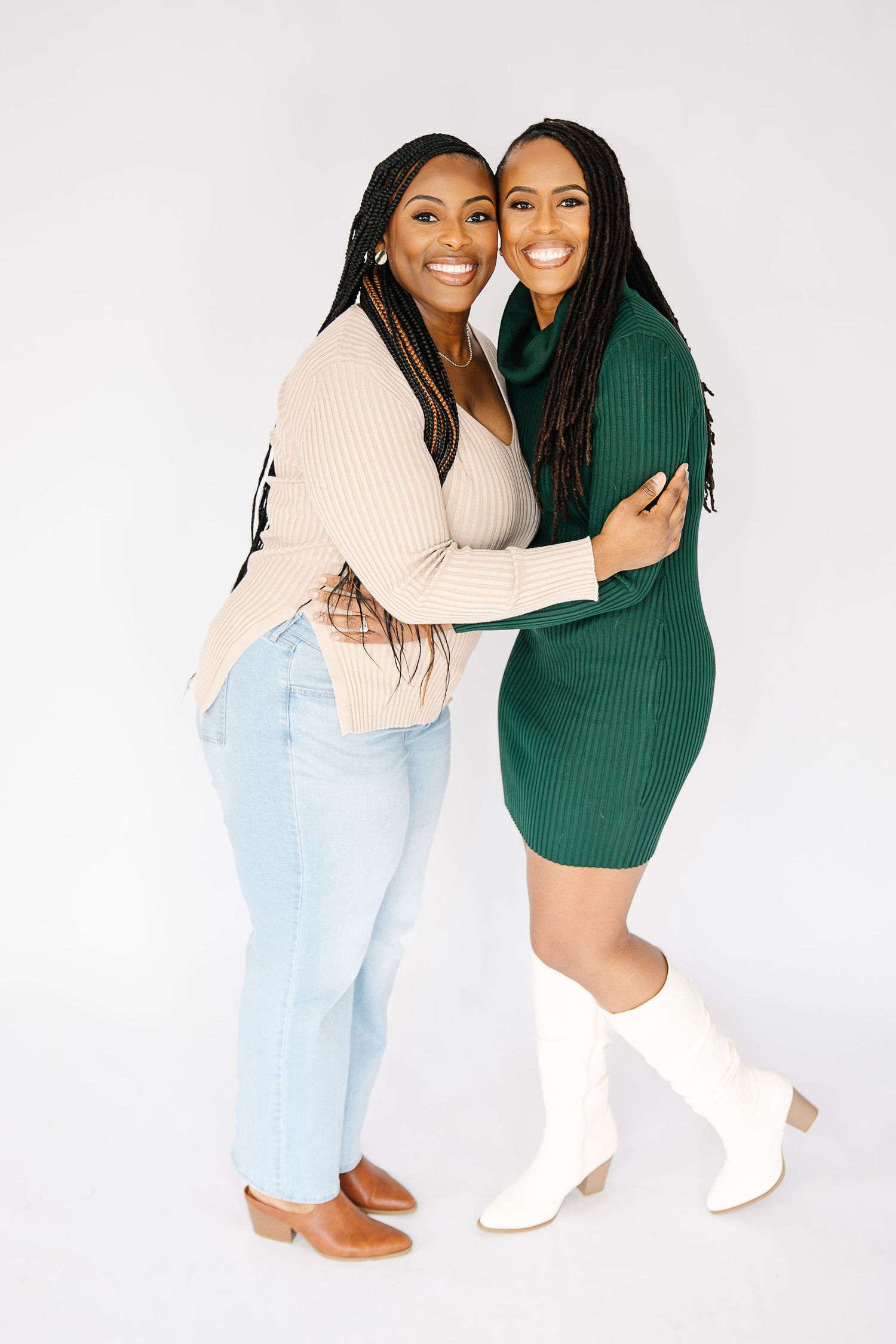 Two people embrace while wearing contrasting outfits of green sweater dress and light denim.