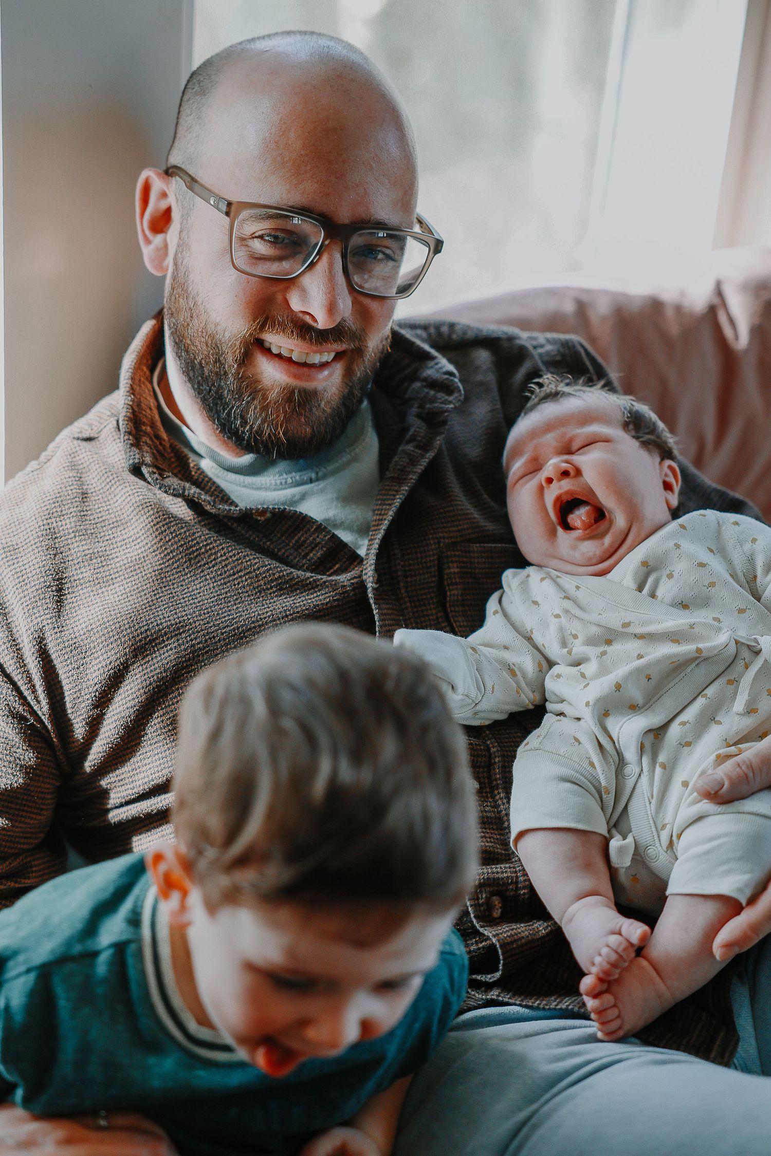 A heartwarming family moment shows a parent and child sharing laughs and cuddles on a couch.