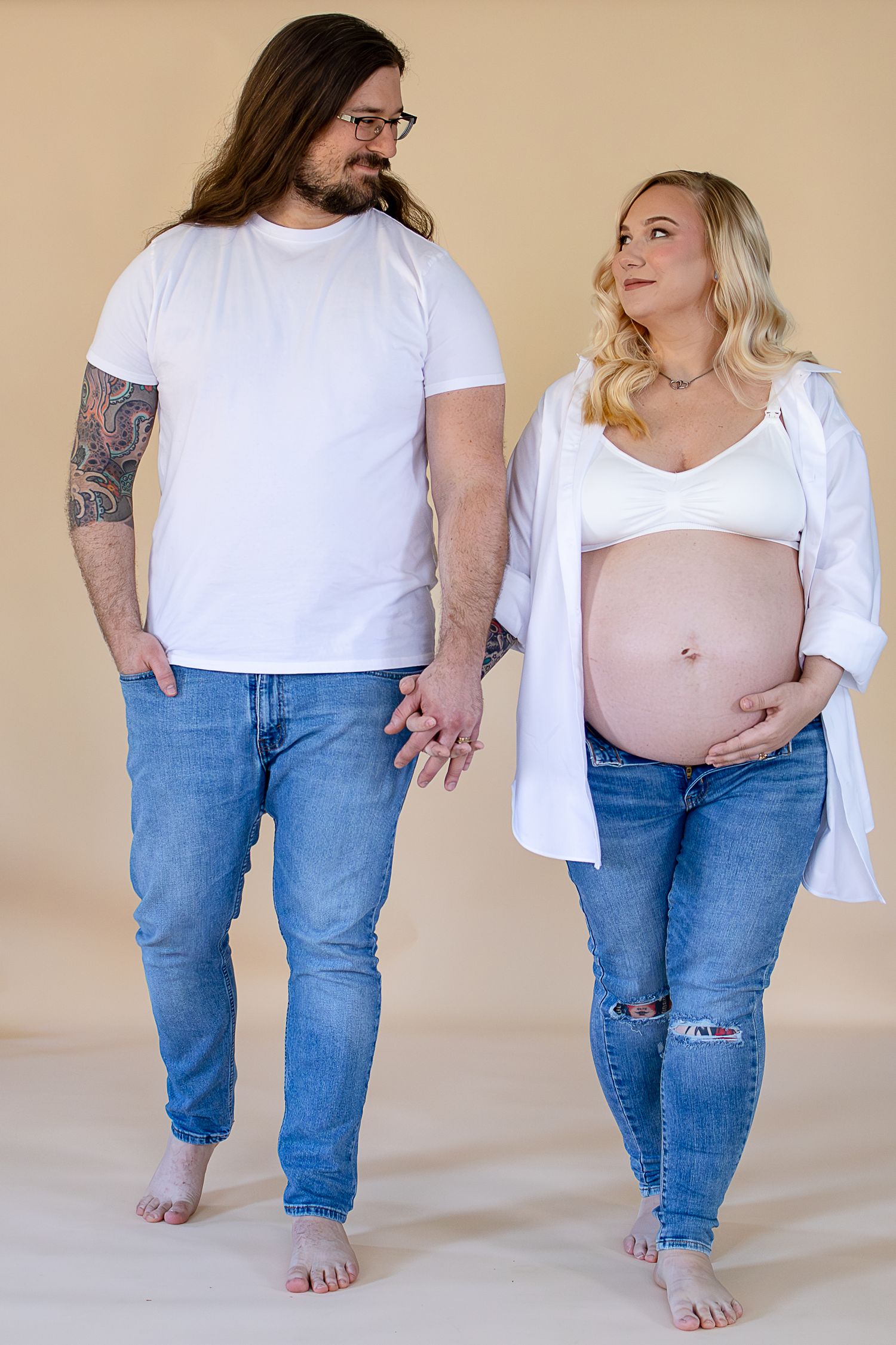 Progression of pregnancy photos showing growing belly in white shirt and jeans from different angles against beige background.