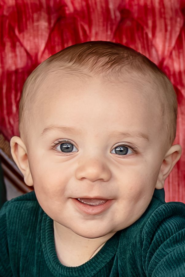 A series of close-up photos showing a baby in a green sweater making playful facial expressions against a red backdrop.