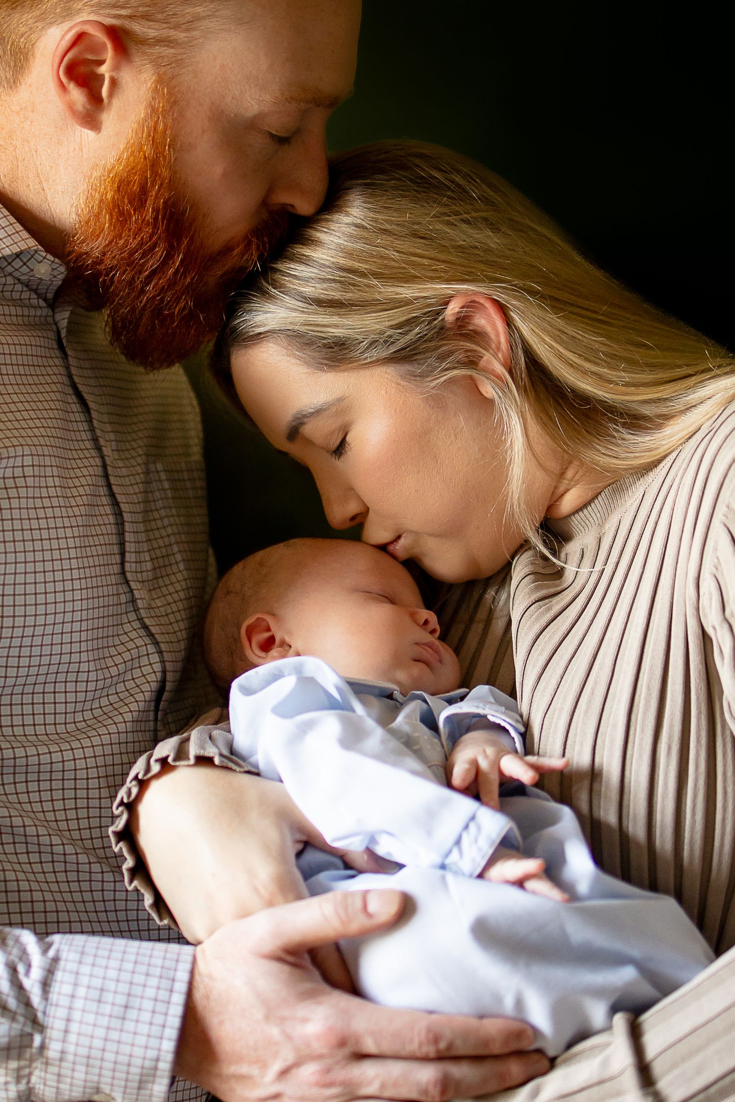Parents tenderly embrace their newborn baby in a series of intimate close-up photos with warm lighting.