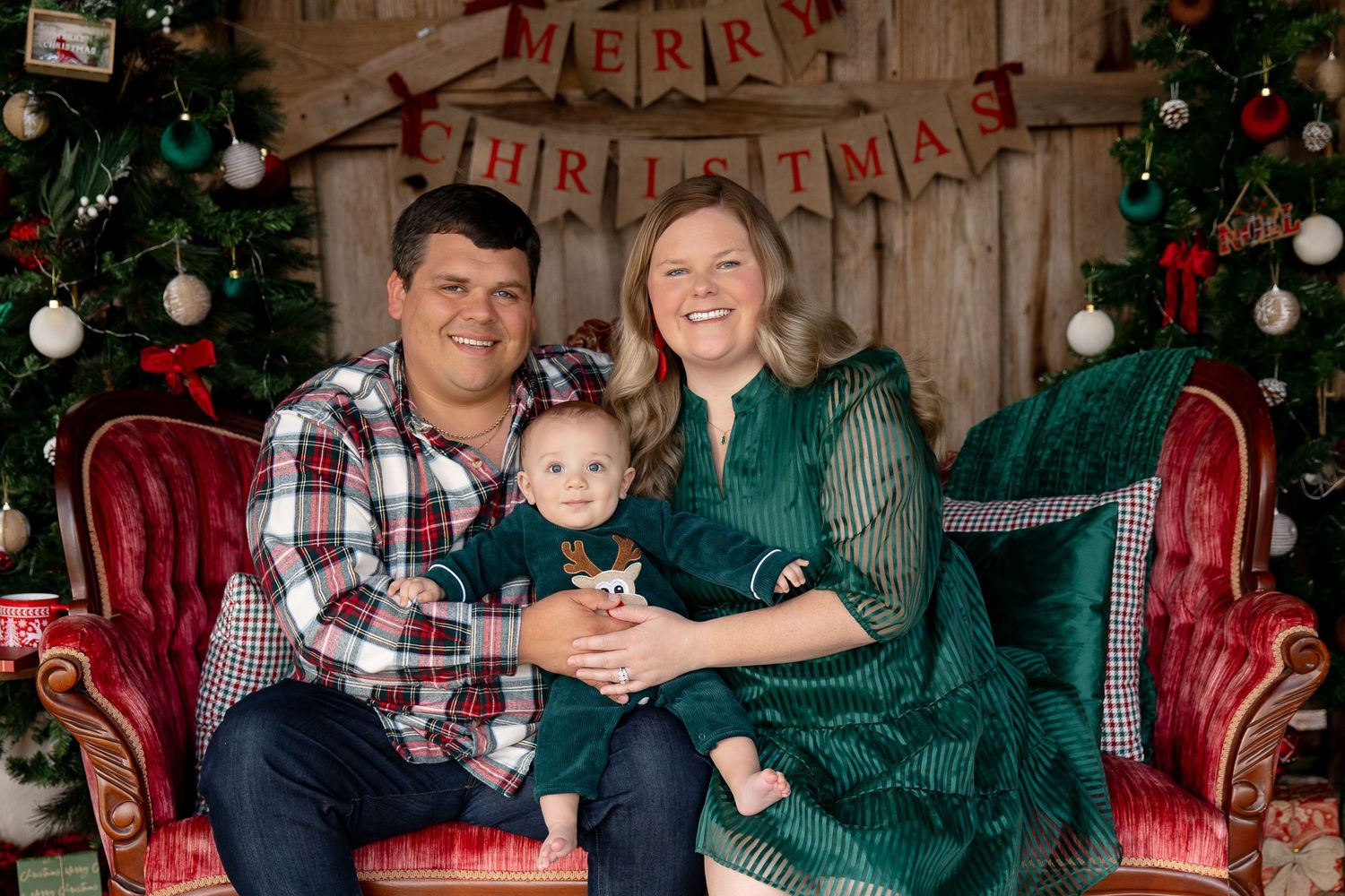 family of three with a baby posing for Christmas pictures