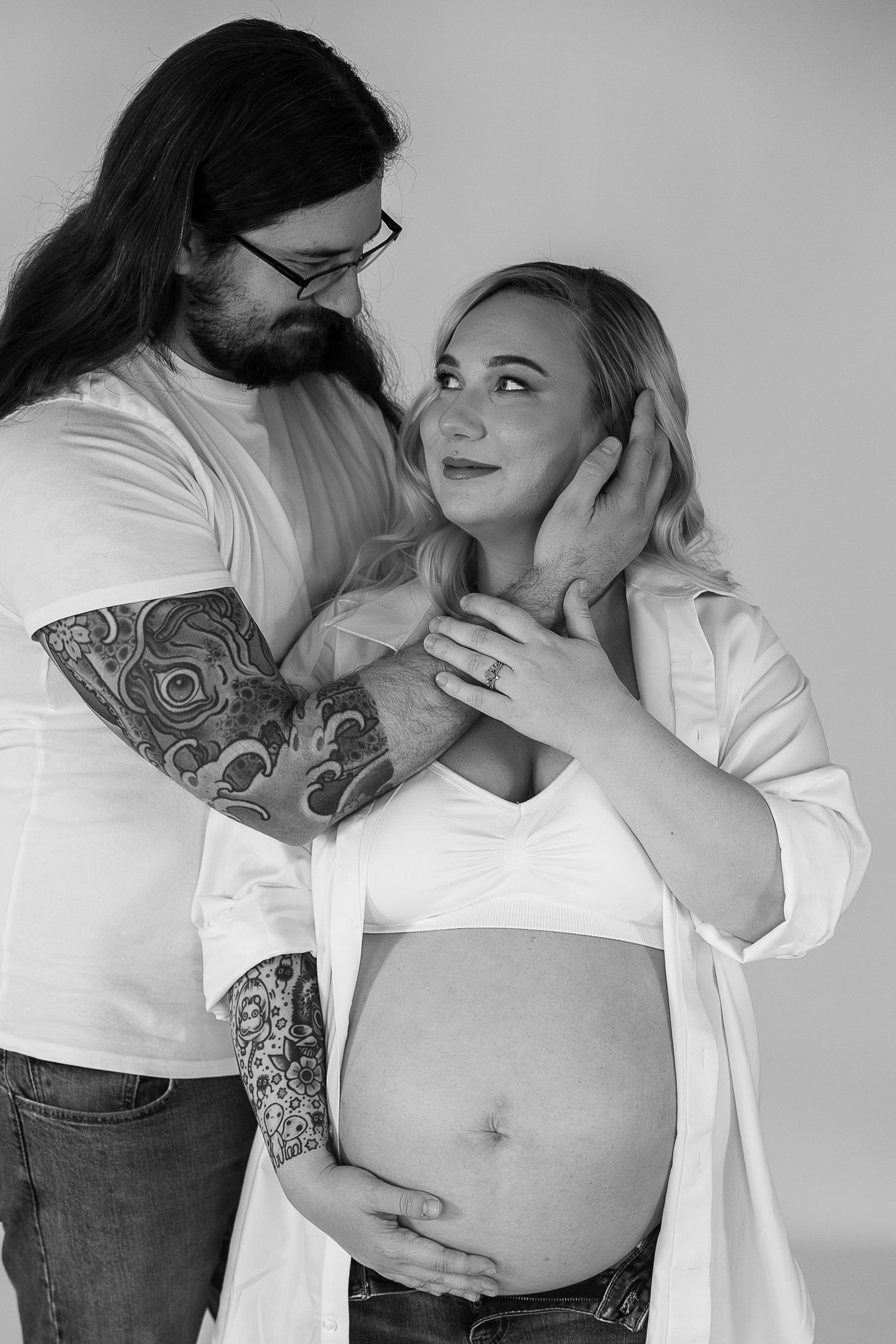 A black and white photo series showing intimate moments between a couple during pregnancy, with gentle embraces and belly touches.