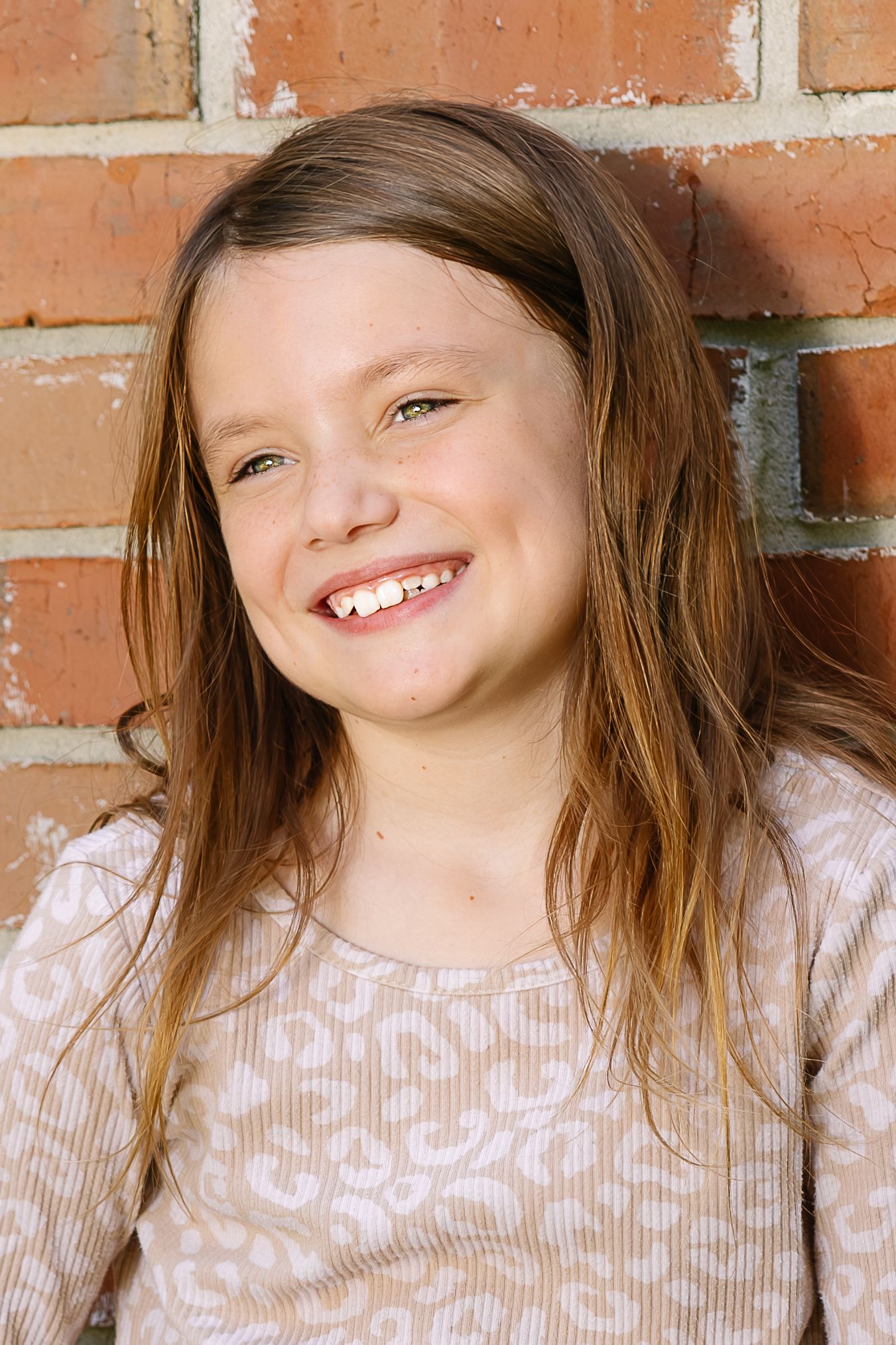 Three sequential photos showing a joyful expression and genuine smile against a brick wall background.