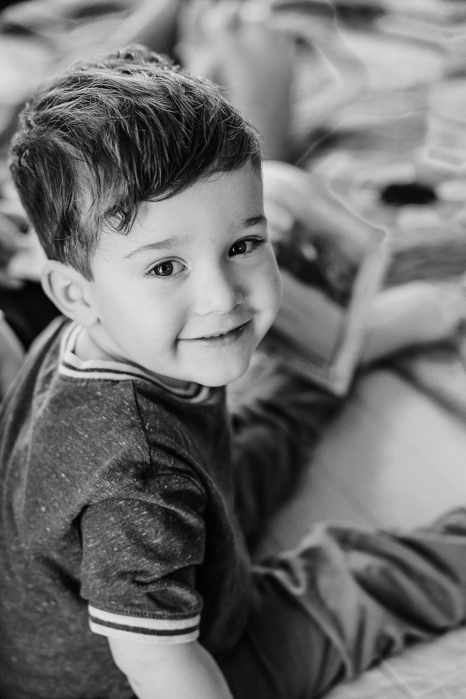 Black and white portrait of a young child with a sweet smile wearing a striped t-shirt while laying down.