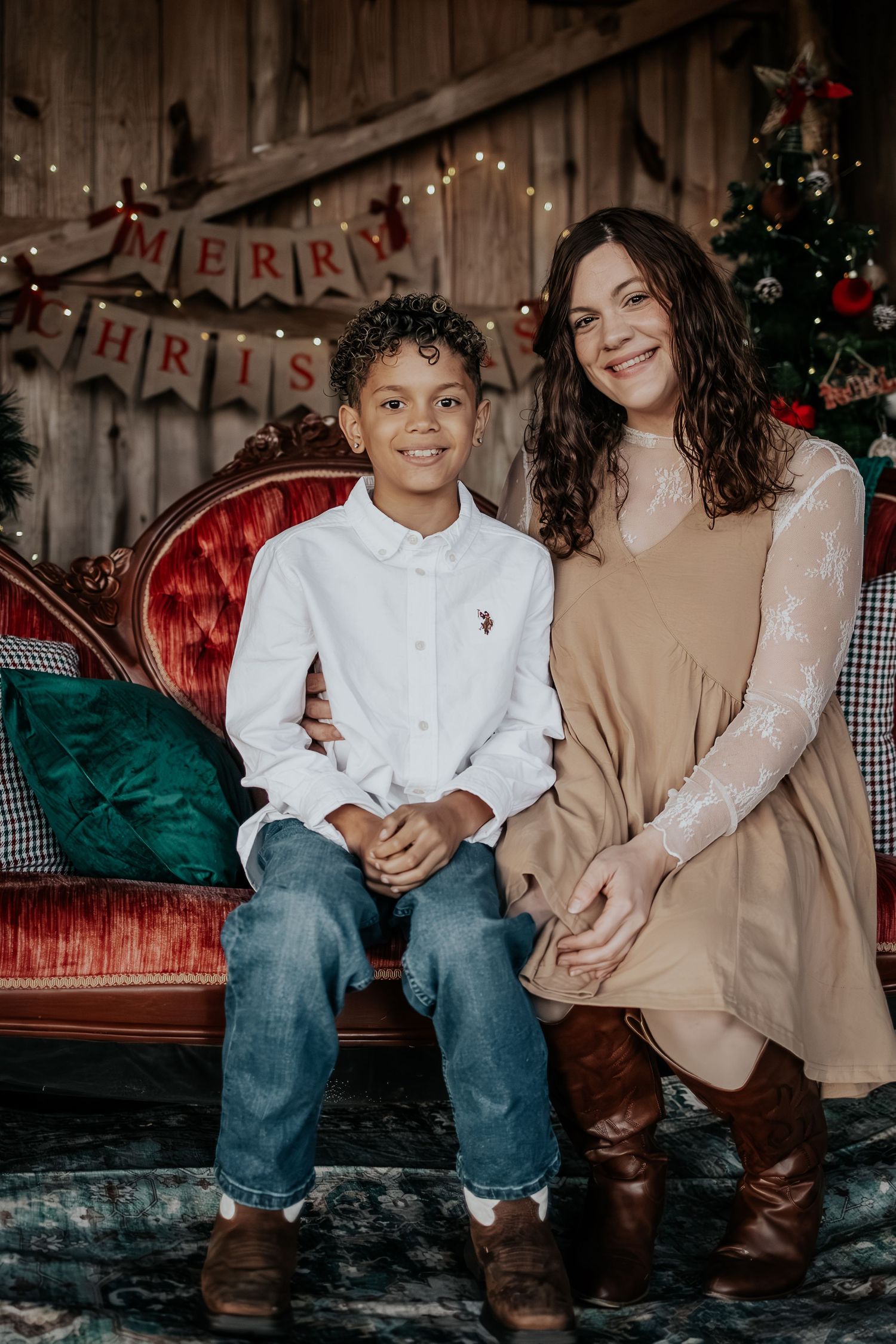 Holiday portrait session showing a warm festive scene with rustic barn wood backdrop and Christmas decorations.