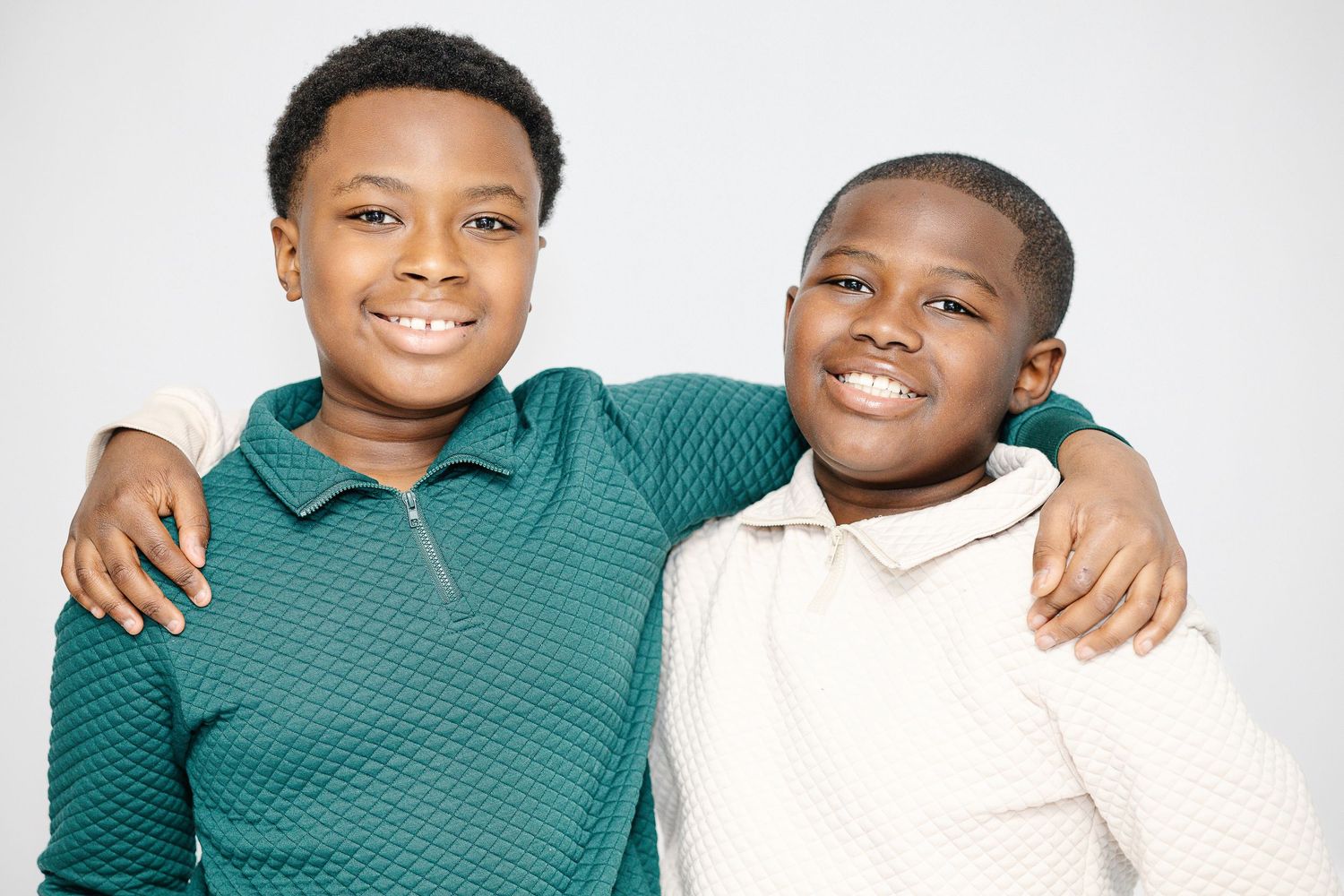 Two people wearing green and white outfits embrace while smiling warmly at the camera.